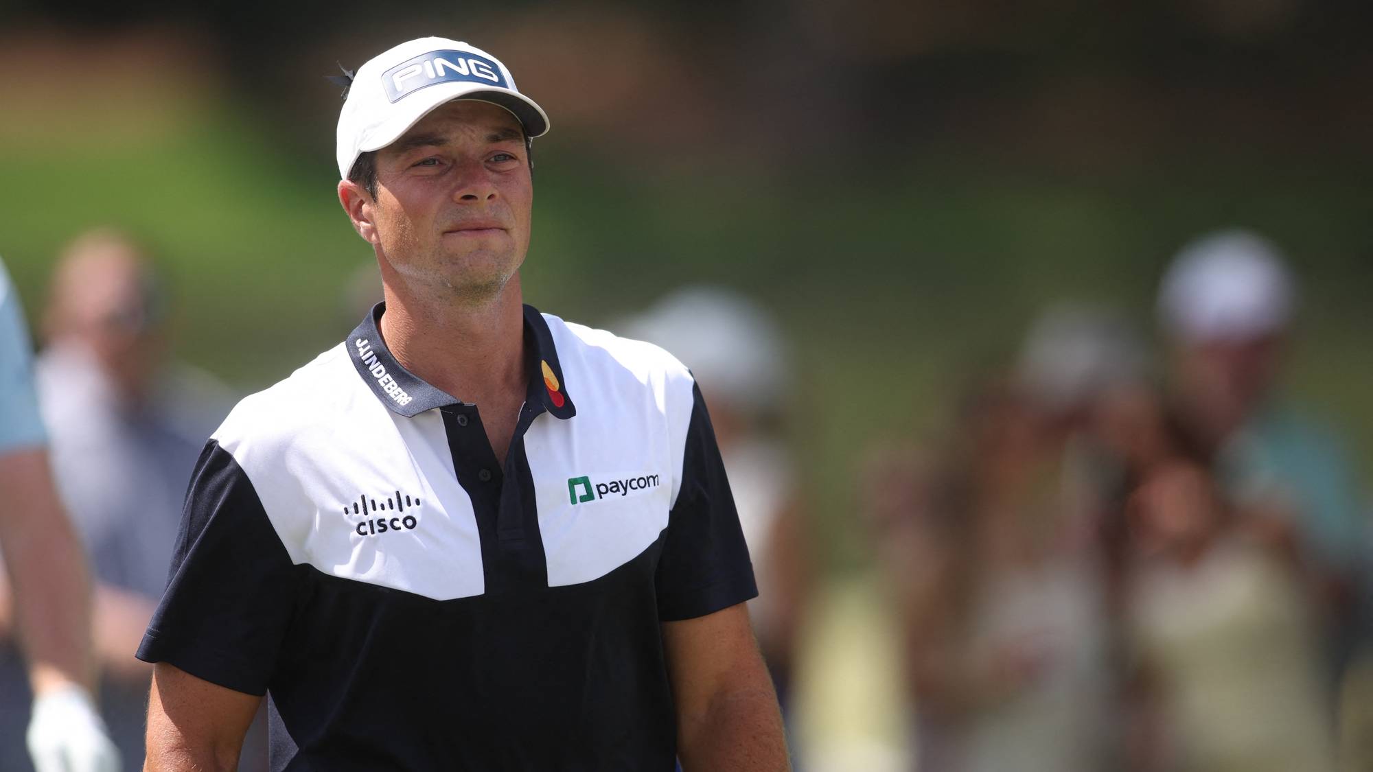 Golfspiller Viktor Hovland på en golfbane. Han går fremover med publikum i bakgrunnen. (Bildebeskrivelsen er laget av en KI-tjeneste)