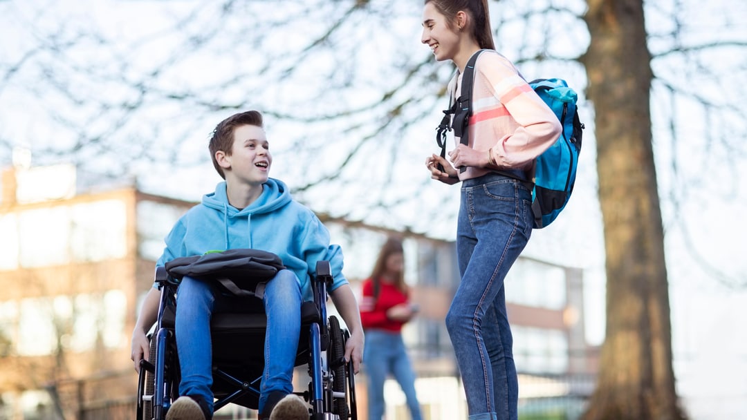 Tenåringsgutt i rullestol snakker med jente