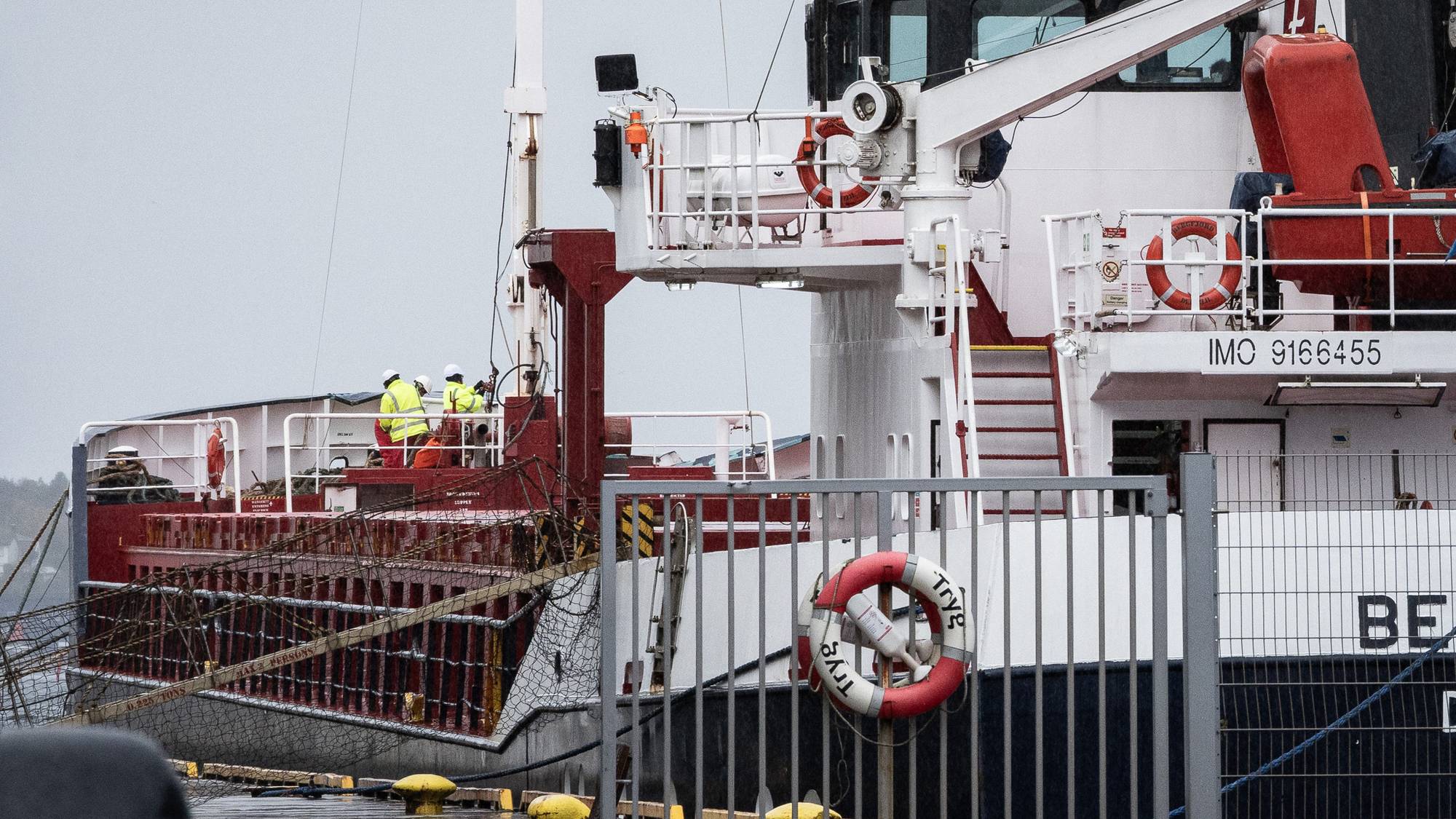 Arbeidere i gule klær om bord på et skip i havn. (Bildebeskrivelsen er laget av en KI-tjeneste)