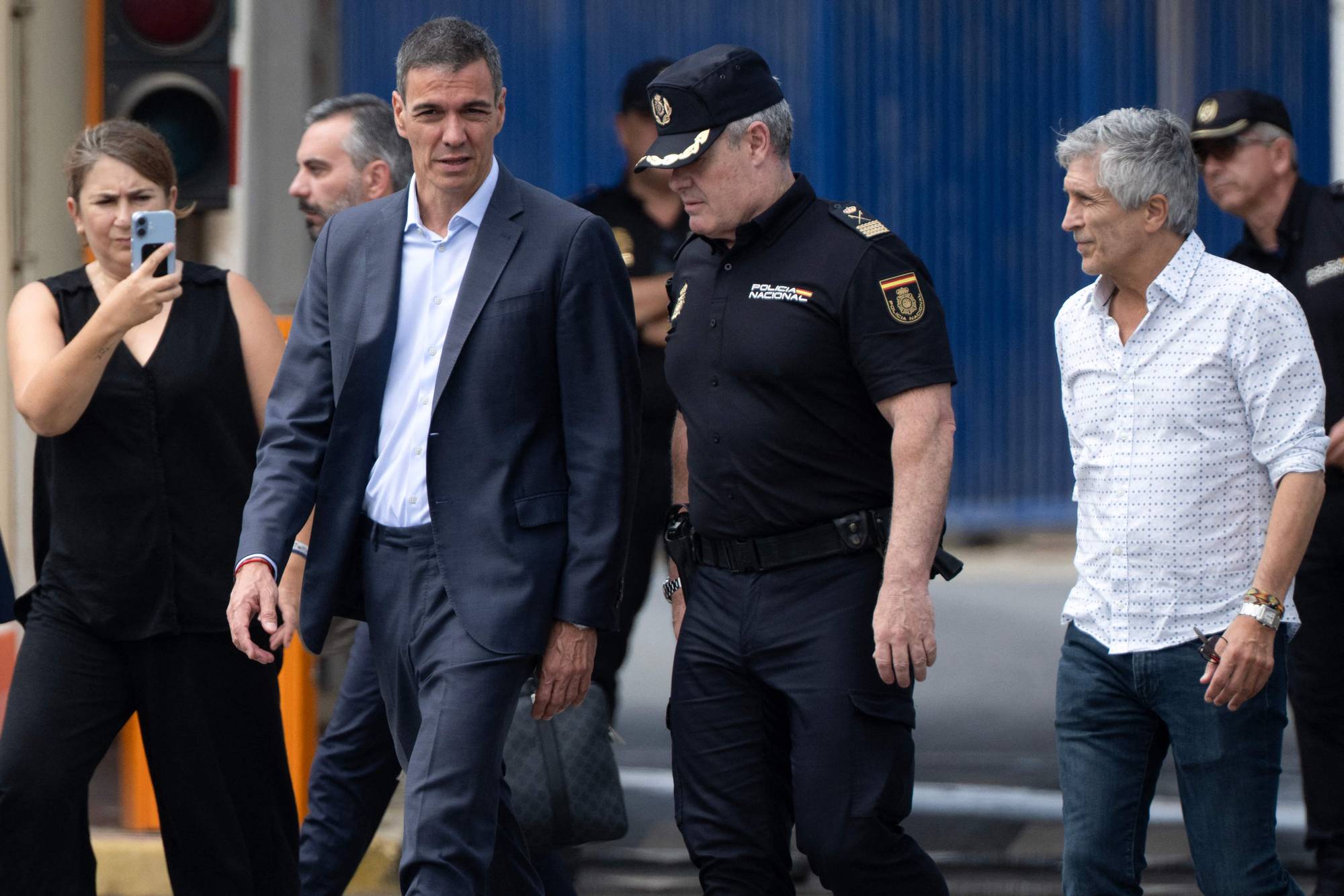 Statsminister Pedro Sánchez går sammen med en politibetjent og andre personer. (Bildebeskrivelsen er laget av en KI-tjeneste)