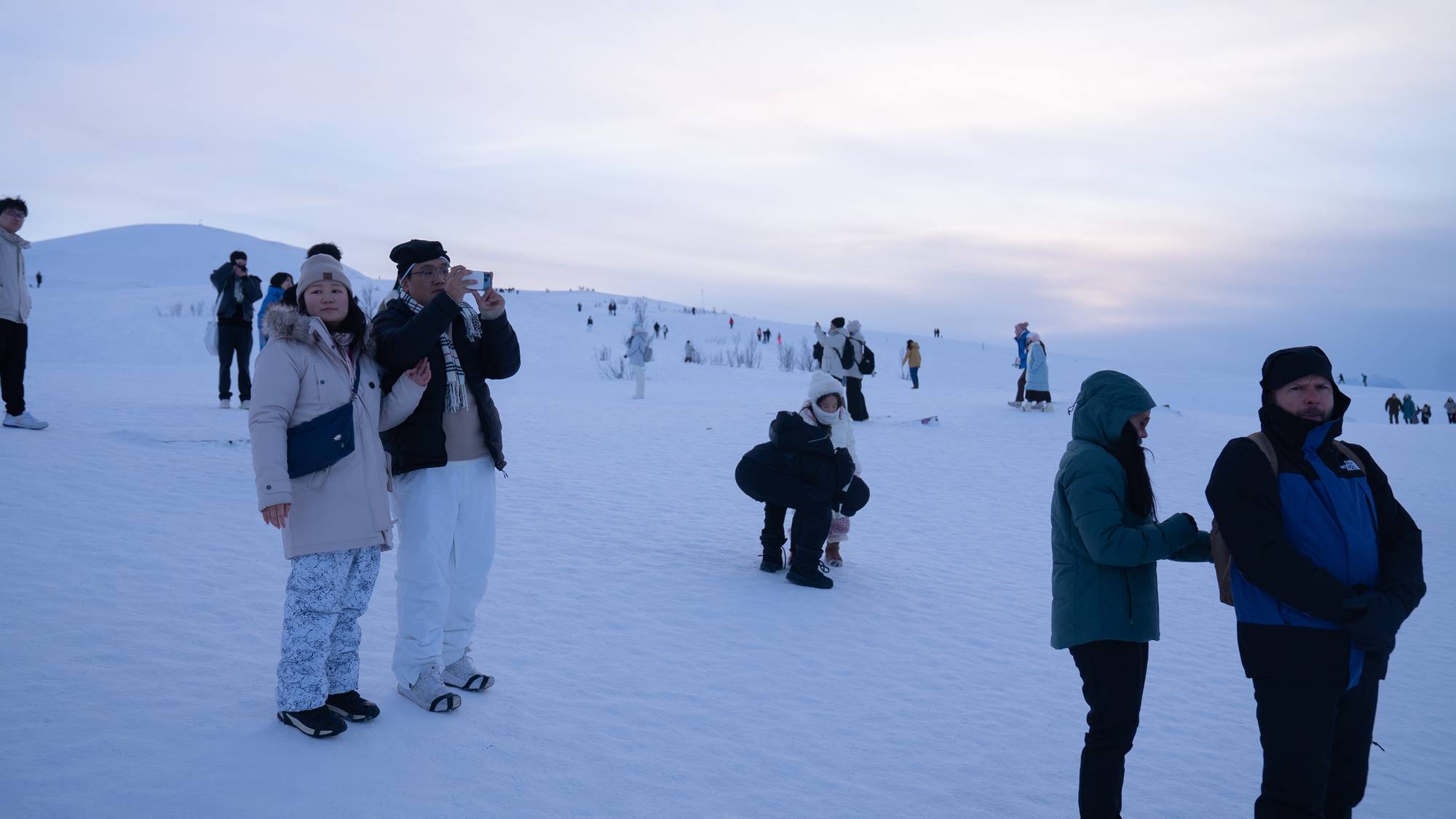 Flere turister står spredt i vinterlige forhold, på Fjellheisen i Tromsø