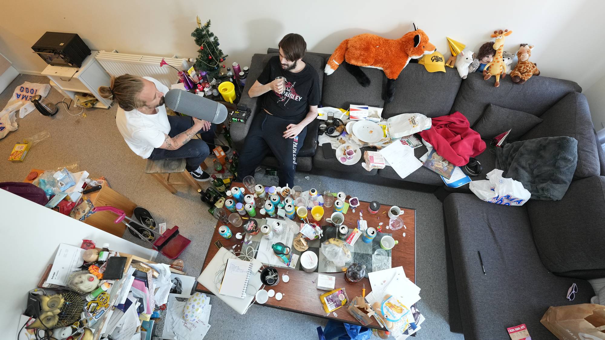 en person i sofa og en ved siden av, sett ovenfra, masse rot