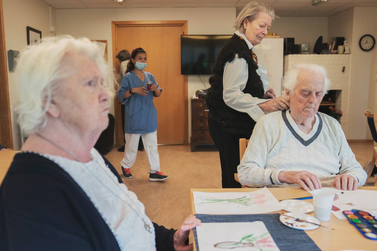 Anne Marie og ekteparet danser og maler ved et stort bord i et oppholdsrom.