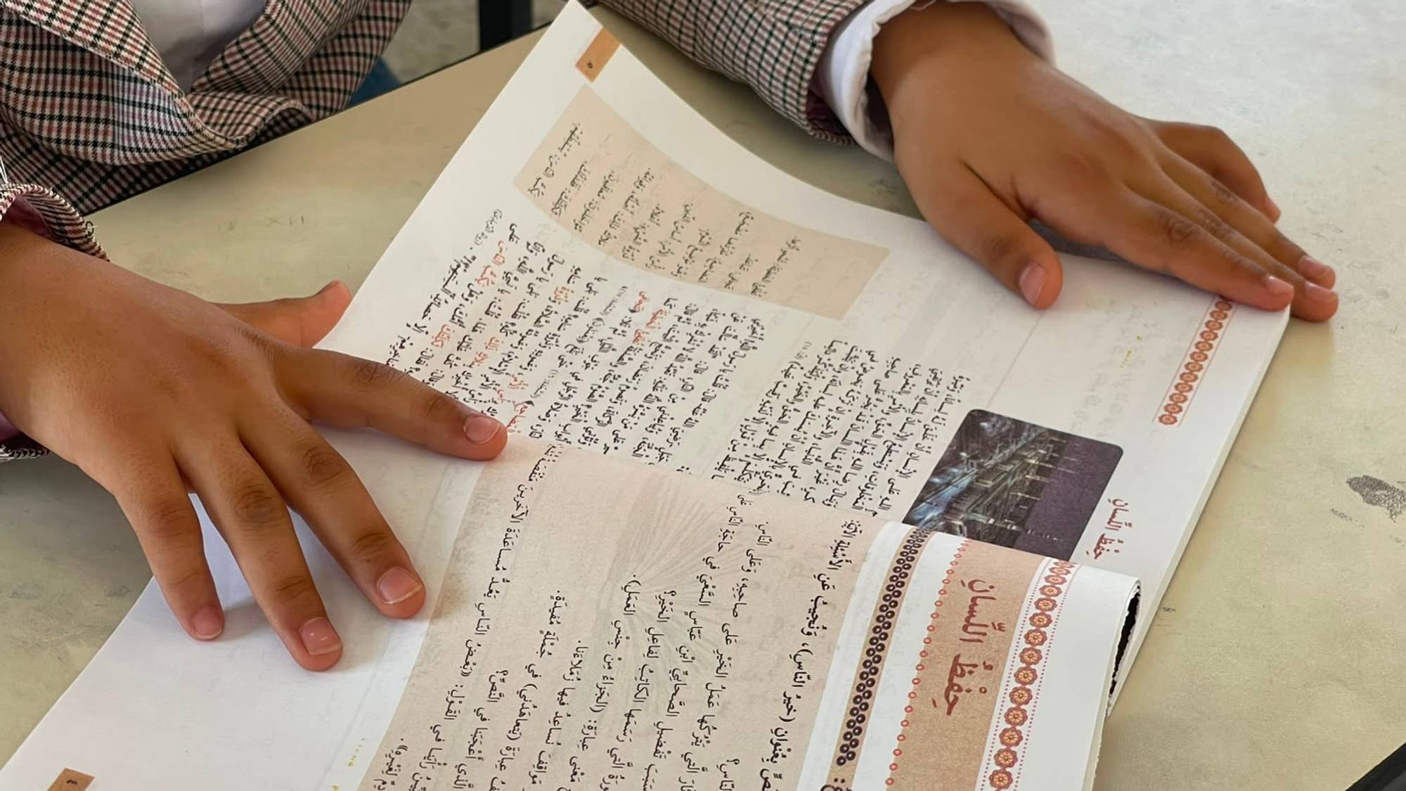 Salma sitter med en fagbok i klasserommet. 