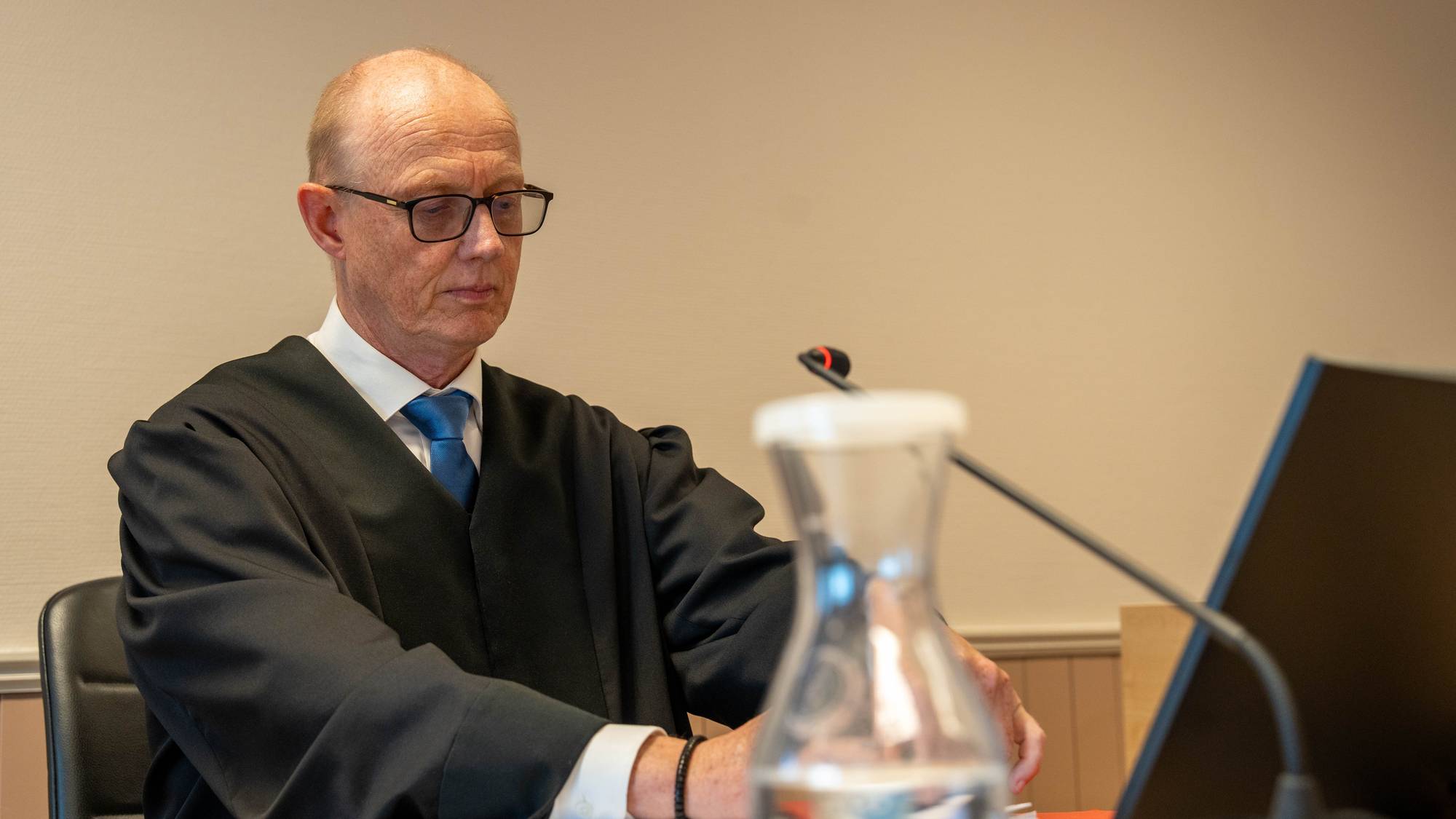 en mann som sitter ved et skrivebord med en datamaskin og et glass vann (Bildebeskrivelsen er laget av en KI-tjeneste)