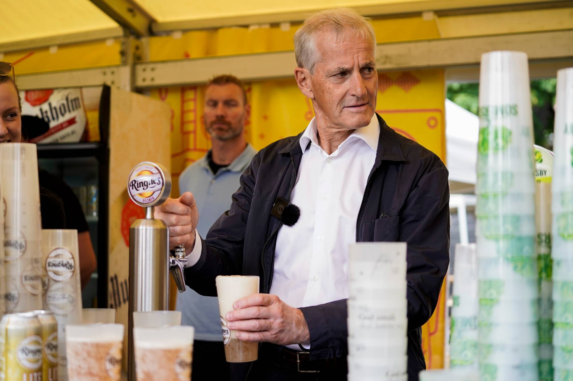 en mann som holder en kopp og et papir med en mann i bakgrunnen