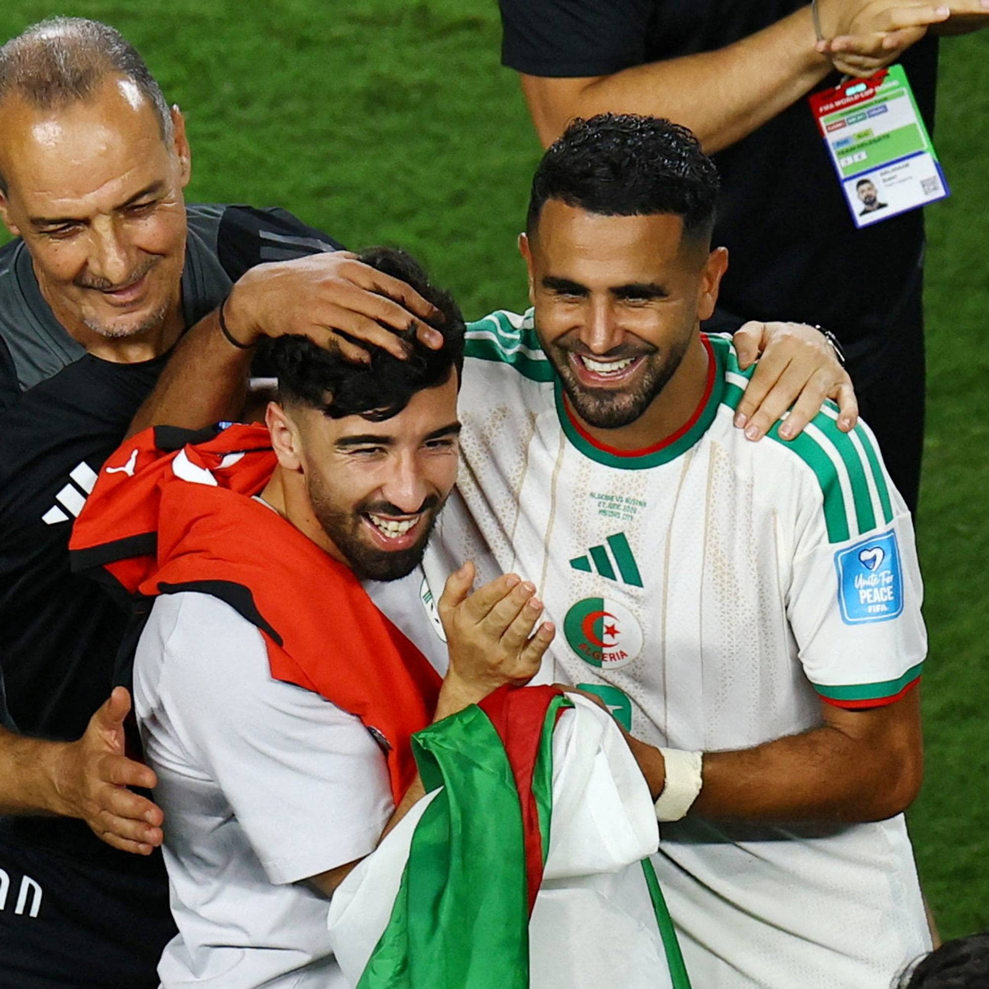 Algeriske fotballspillere og en trener feirer sammen på banen med et algerisk flagg. (Bildebeskrivelsen er laget av en KI-tjeneste)