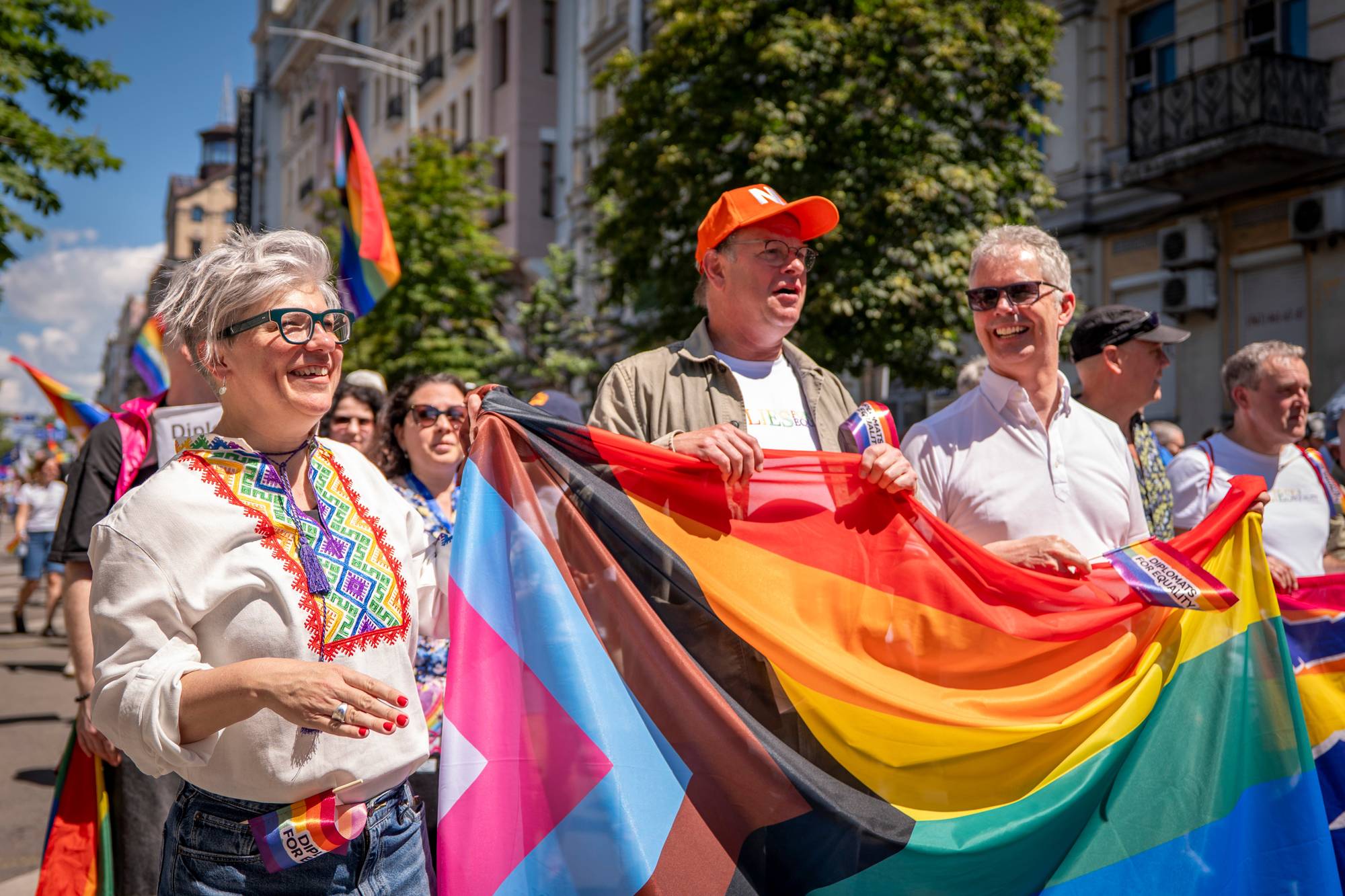 Personer holder et Pride-flagg i en gateparade. 