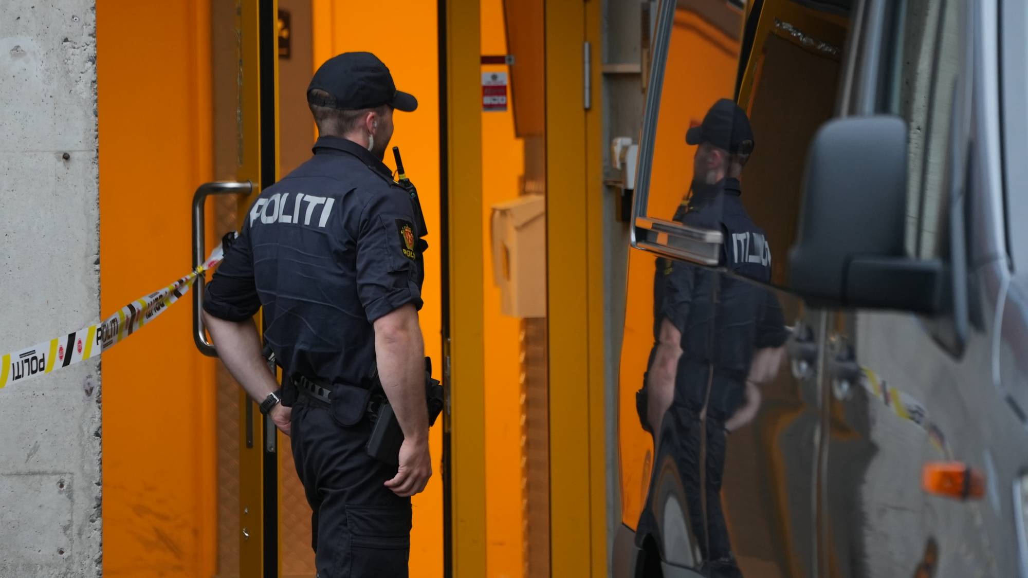 Politibetjent står vakt ved en avsperret inngang.