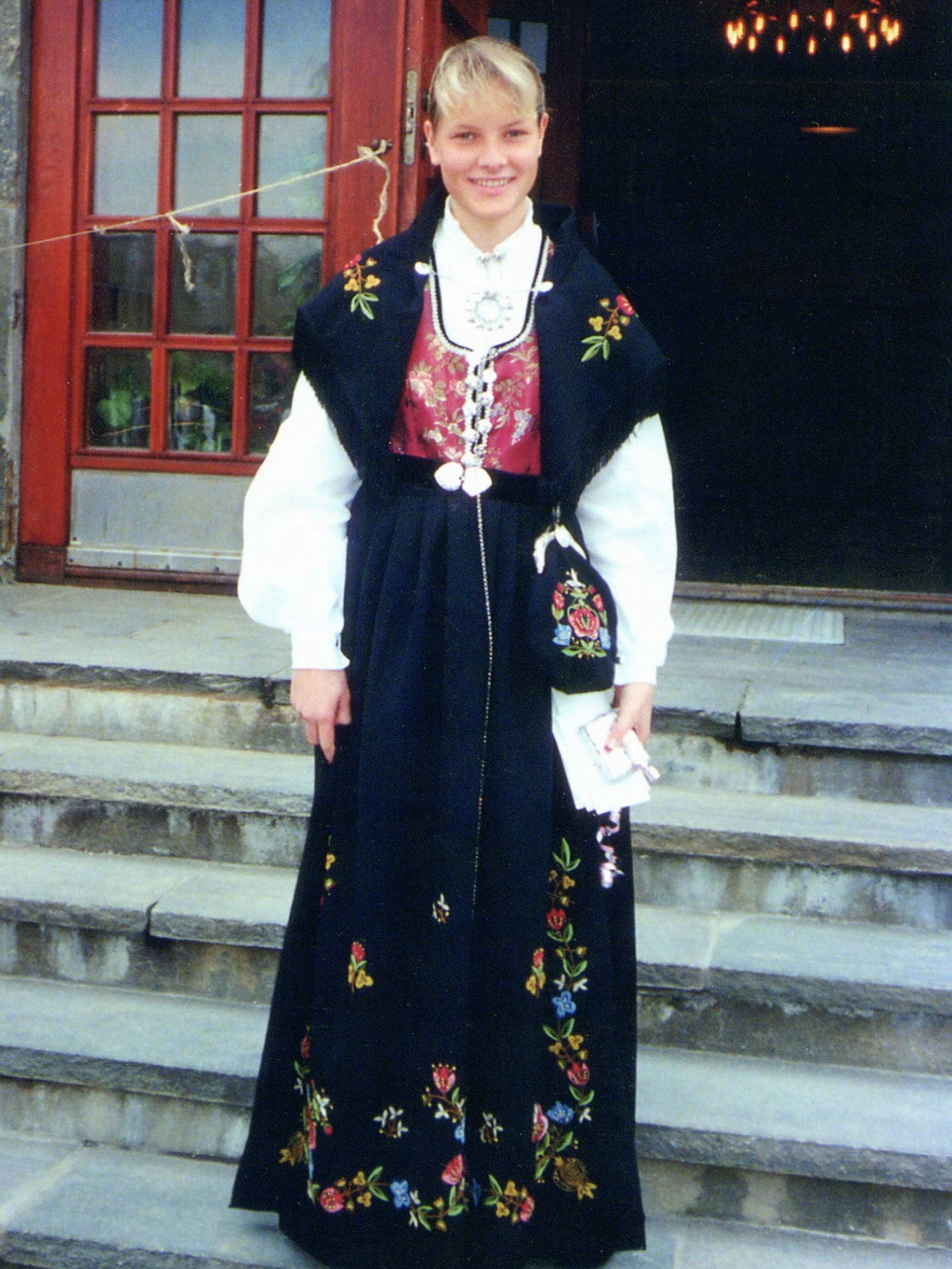 Mette-Marit Tjessem Høiby i rogalandsbunad står på trappen til Vågsbygd kirke, der hun ble konfirmert i 1988