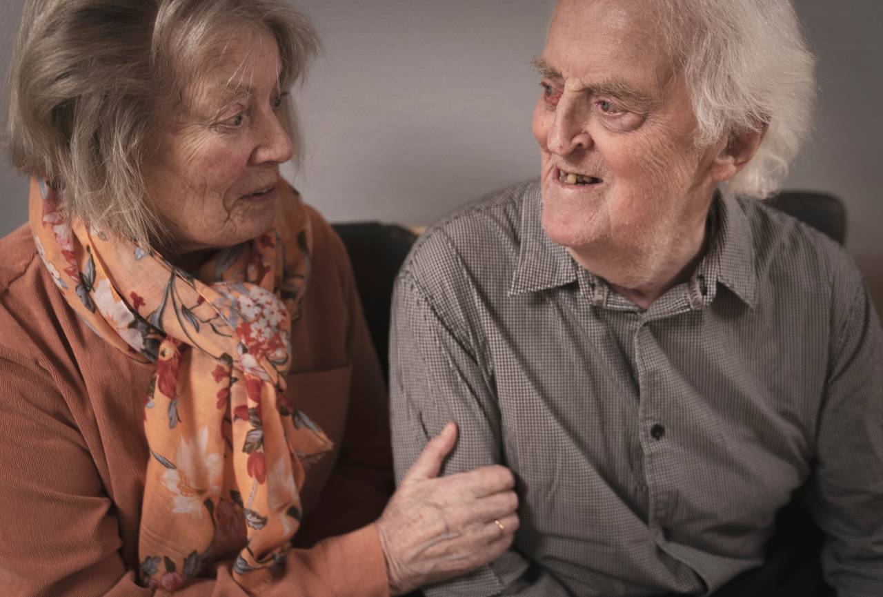 Ekteparet sitter sammen i en sofa og ser på hverandra