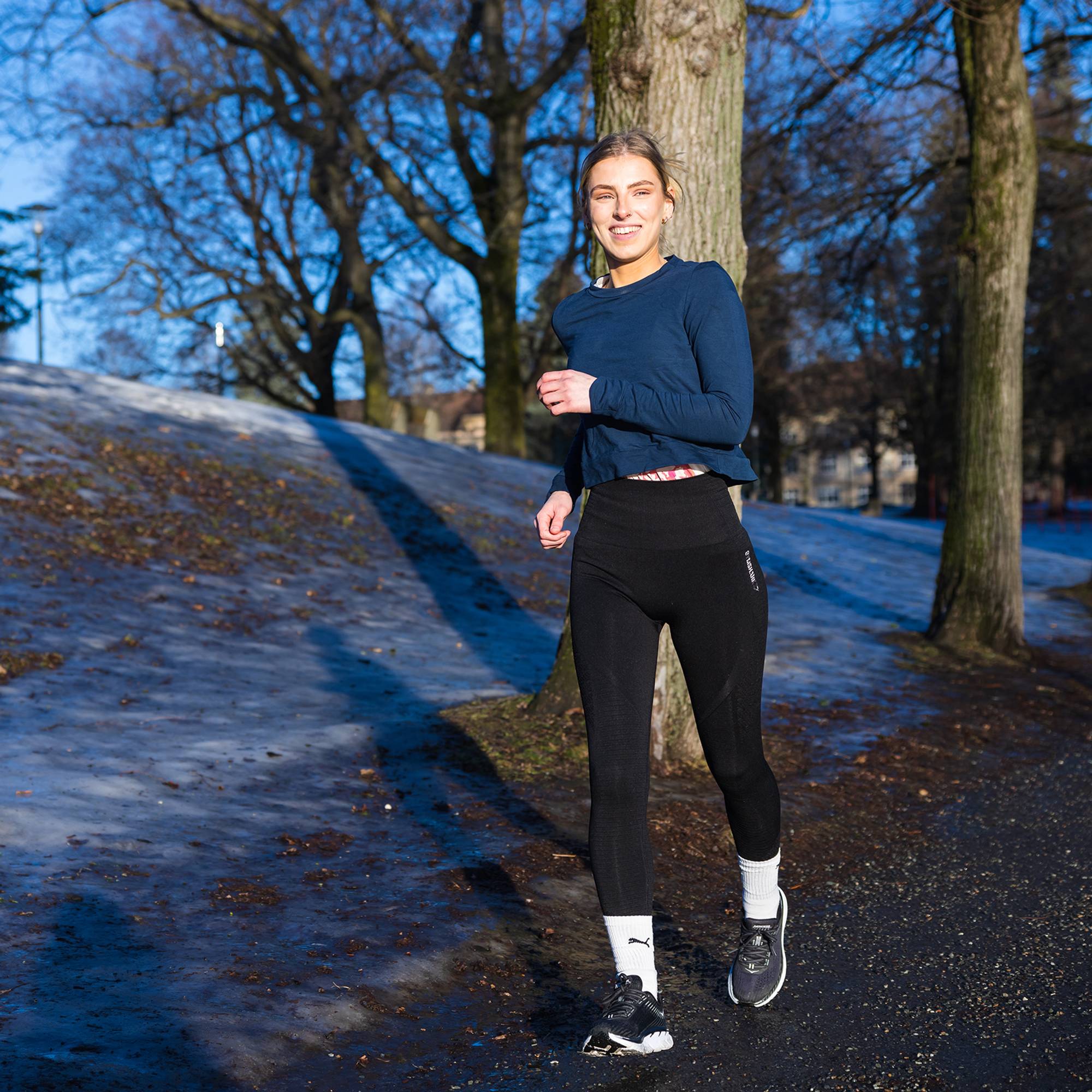 Synne smiler mens hun løper langs Torshovparken i Oslo. Sola lyser opp ansiktet hennes.