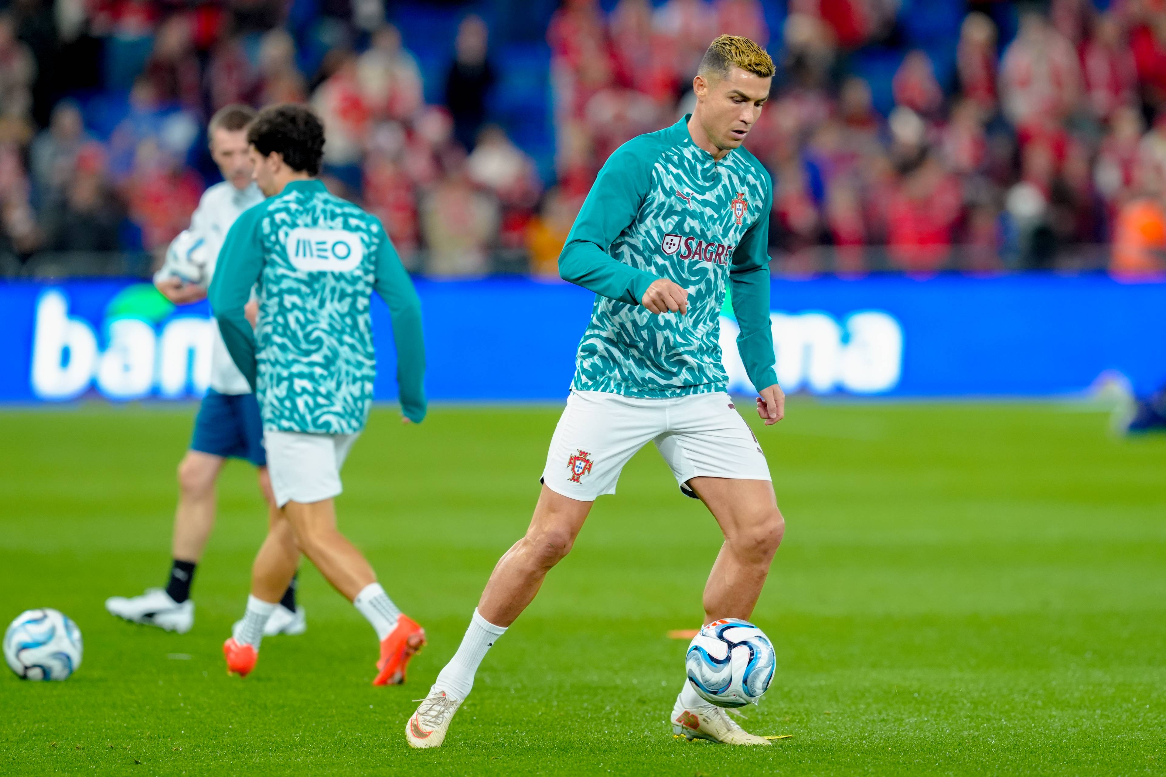 Cristiano Ronaldo varmer opp med ball på en fotballbane i Portugal-drakt. (Bildebeskrivelsen er laget av en KI-tjeneste)
