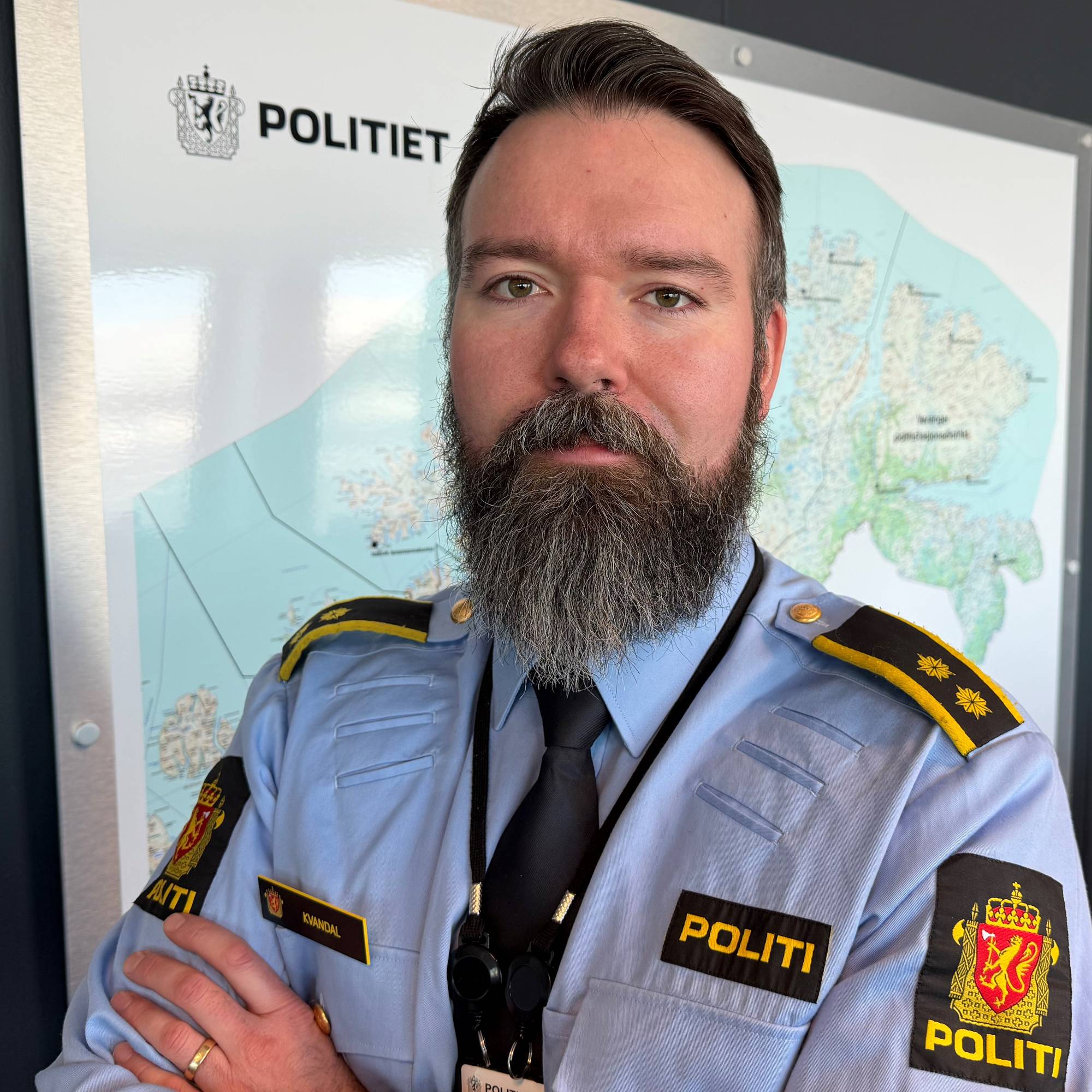 En mann i politiuniform ser i kamera. Han har stort skjegg og ser alvorlig ut.