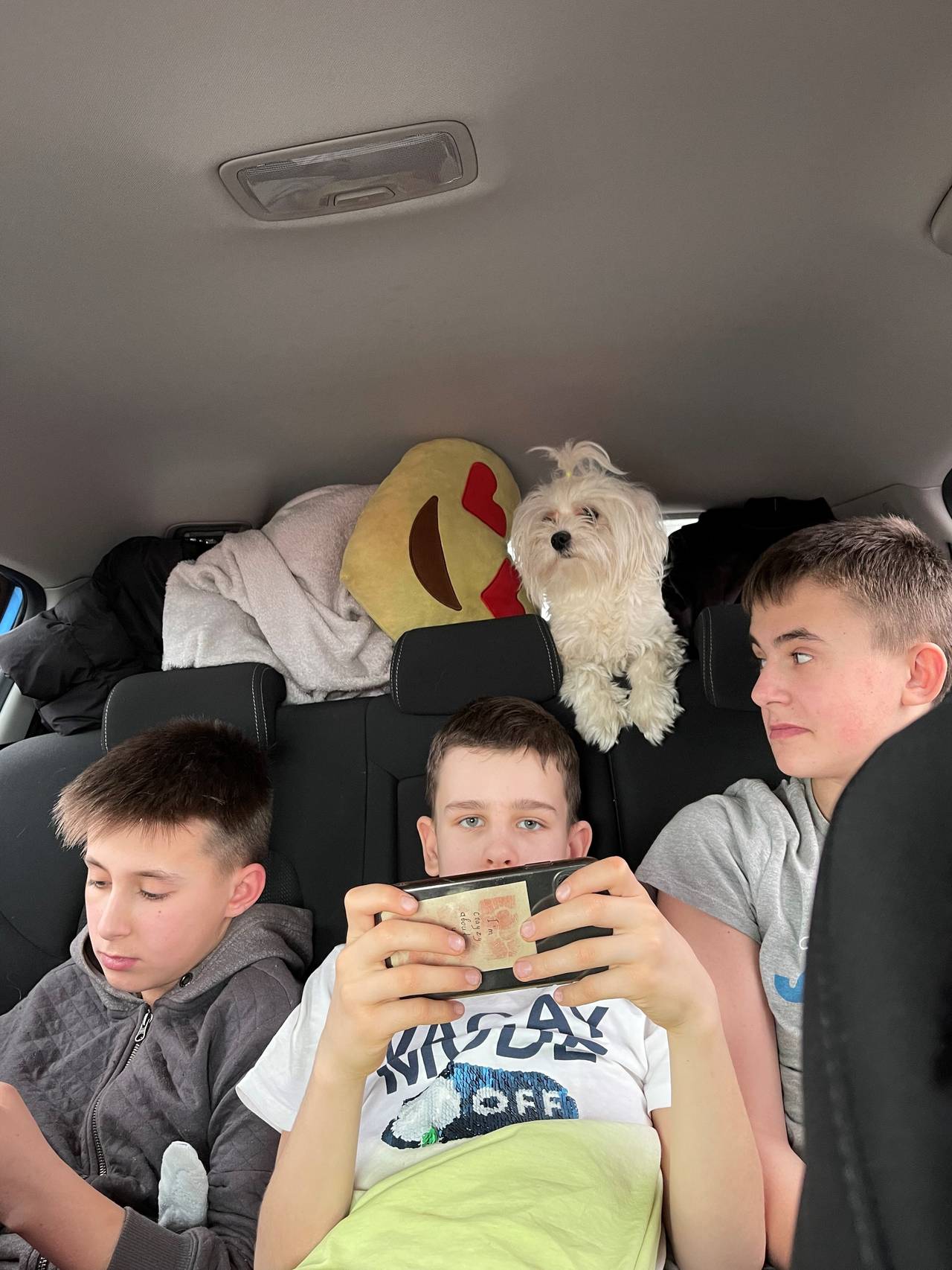 Yevheniy (13), David (12) og Bohdan (15) i baksetet på bilen mens de flykter fra Ukraina. 