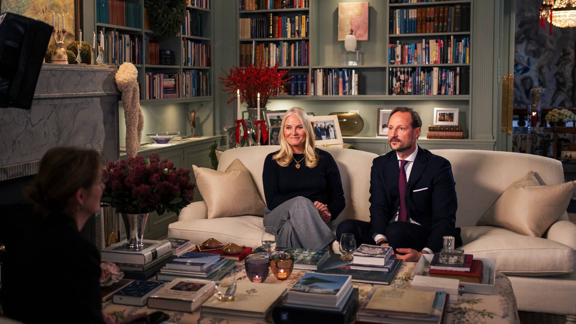 Kronprinsparet sitter i en lys sofa hjemme på Skaugum og blir intervjuet av NRK til "Året med kongefamilien 2025"