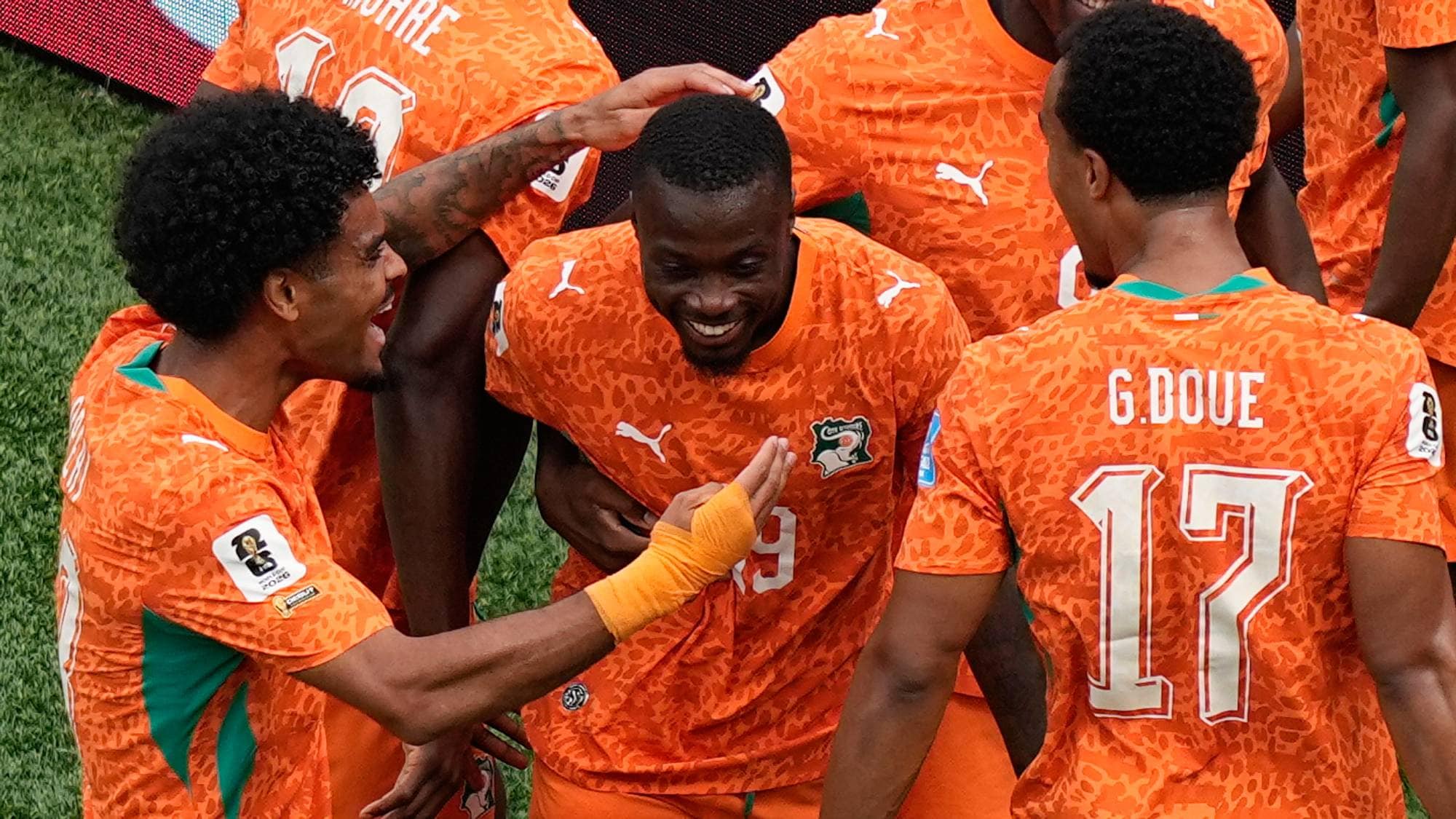Elfenbenskystens fotballspillere feirer i oransje drakter på gressbanen. (Bildebeskrivelsen er laget av en KI-tjeneste)