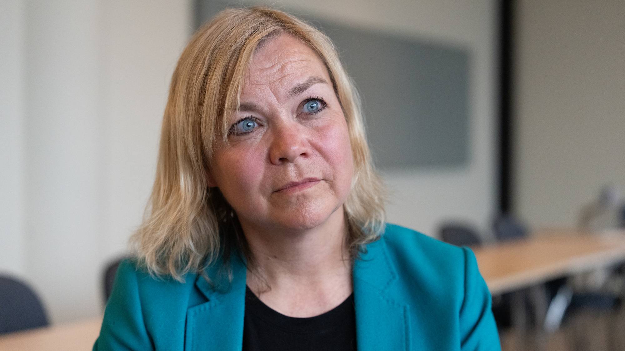 Kvinne med lyst hår og blå øyne ser ut i lufta