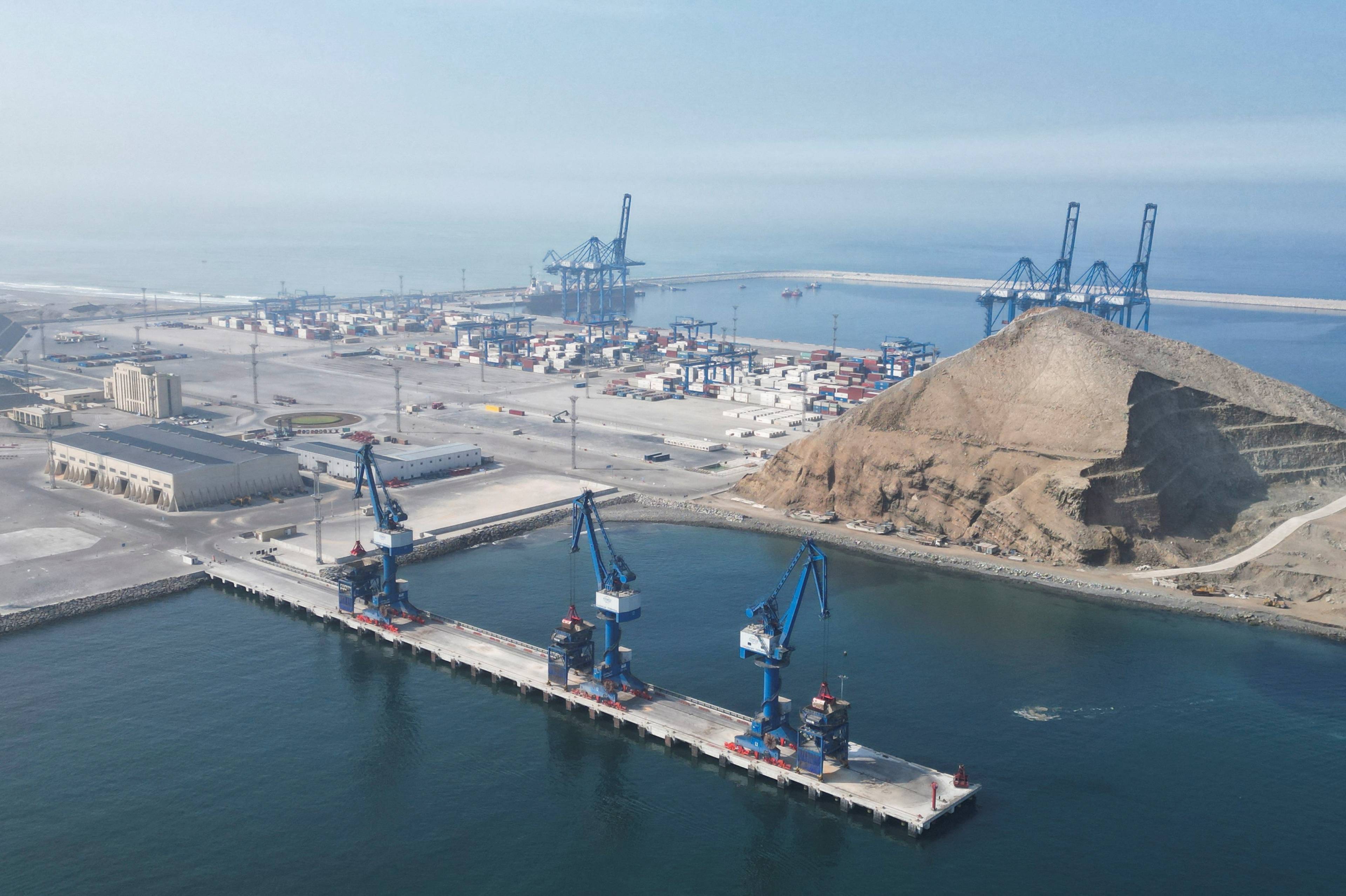 Flyfoto av en dypvannshavn med containere, havnekraner og en stor haug med steinmasser. (Bildebeskrivelsen er laget av en KI-tjeneste)