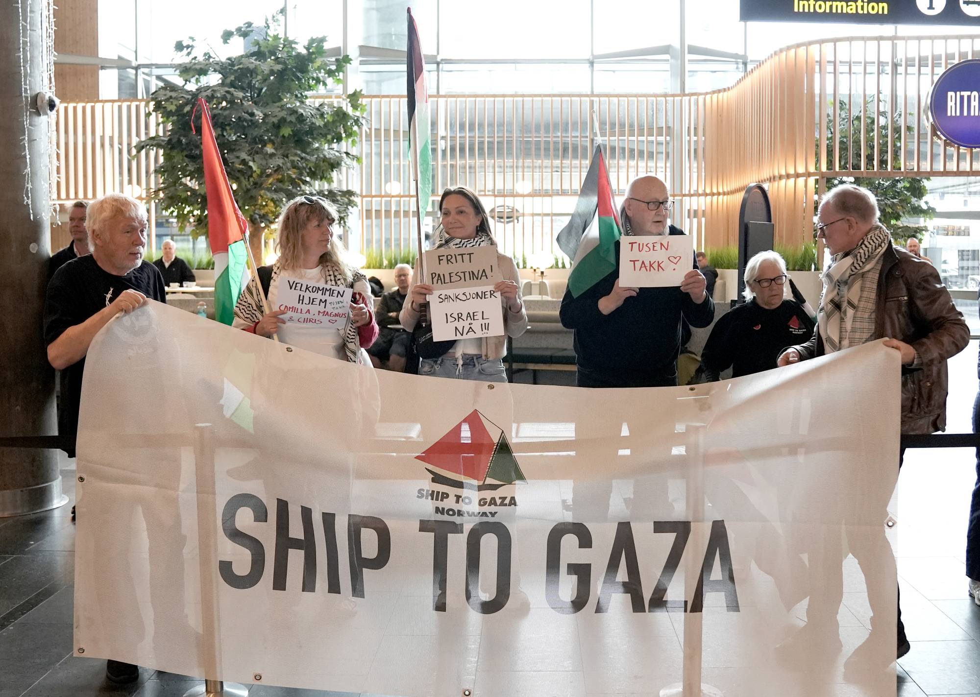 Mennesker står med palestinske flagg og banner med påskriften Ship To Gaza