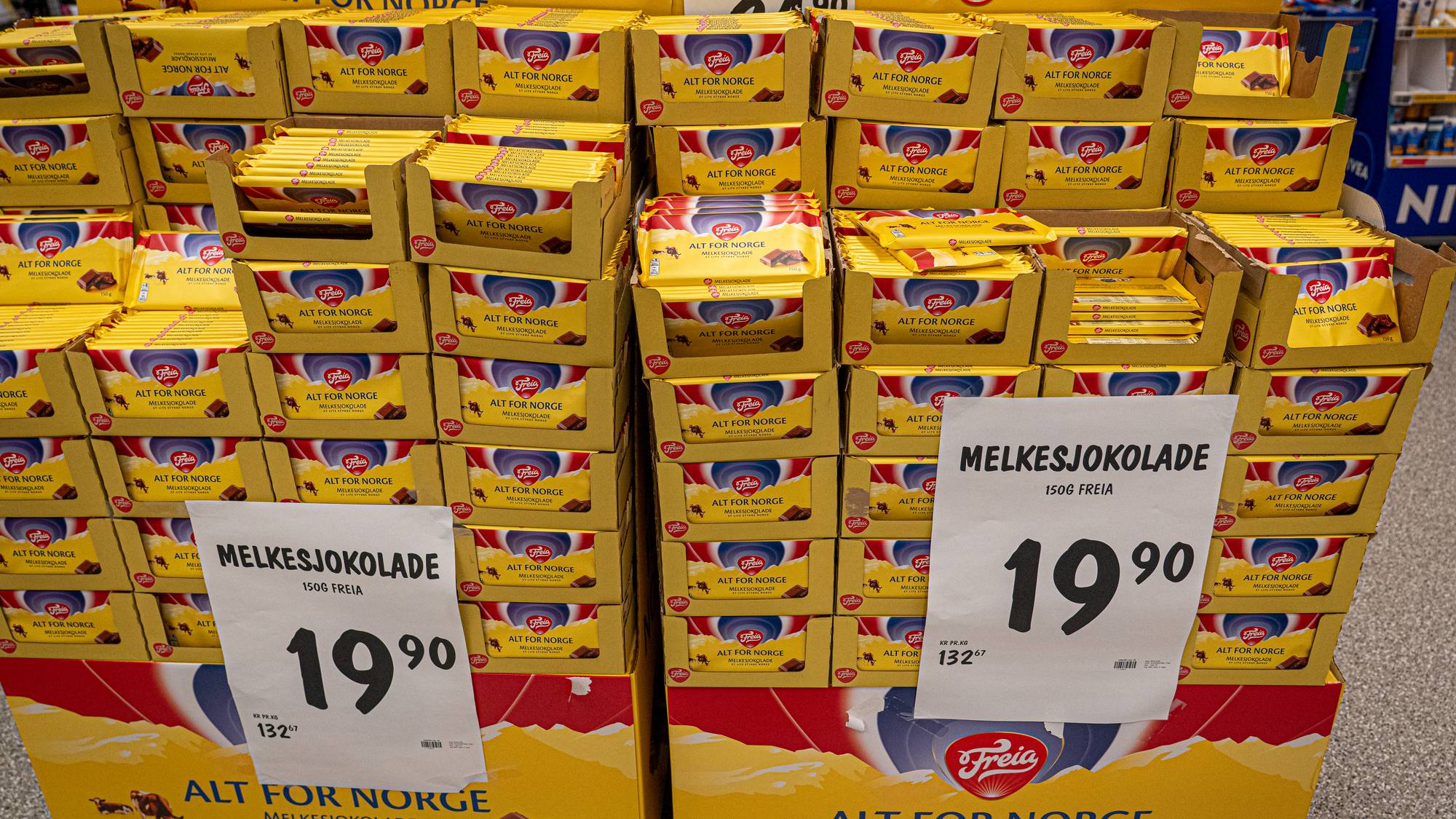 Utstilt Freia melkesjokolade i butikk. Emballasjen har teksten "Alt for Norge" og det norske flagget. Et prisoppslag viser 19,90 kr for 150g Freia melkesjokolade. (Bildebeskrivelsen er laget av en KI-tjeneste)