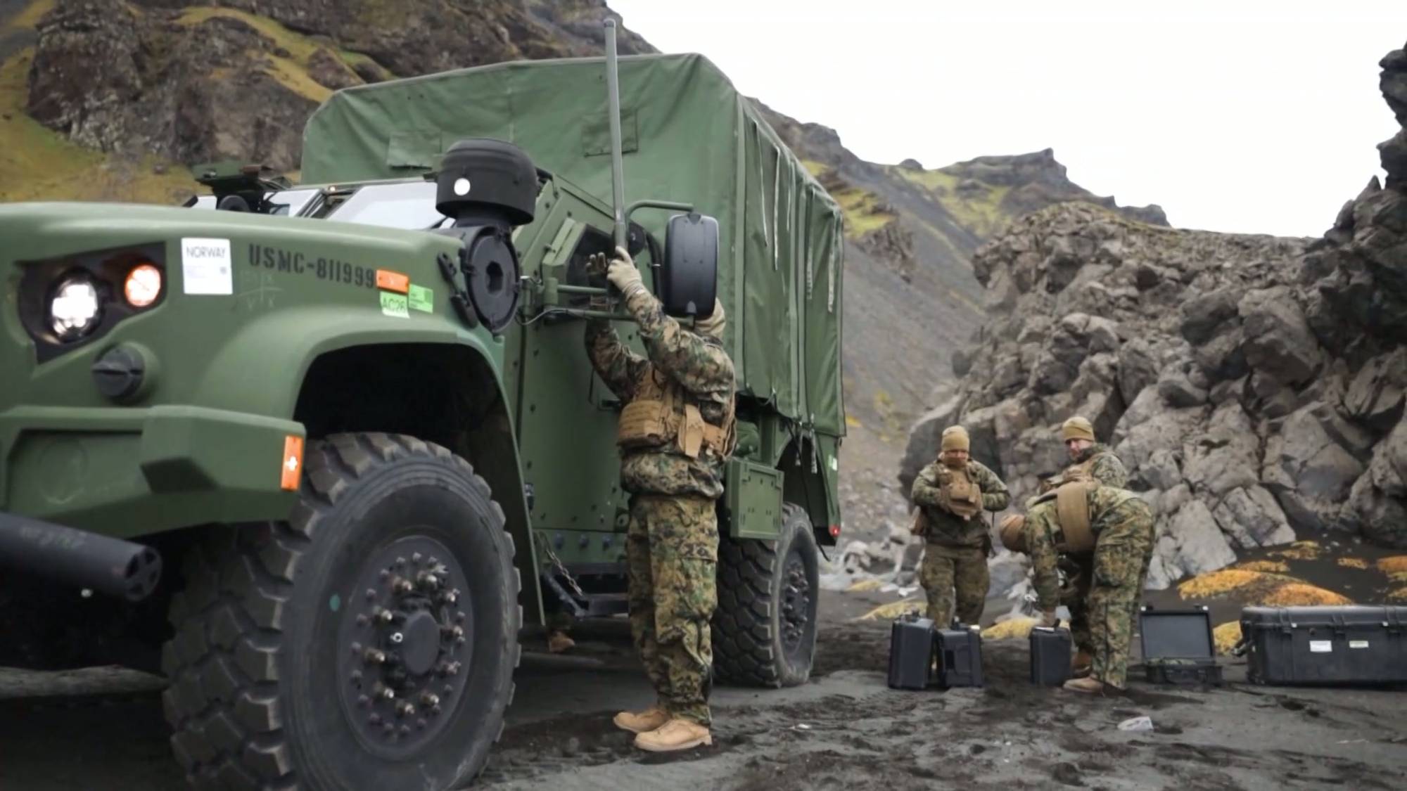 Soldater i uniform ved et militærkjøretøy i et øde landskap. (Bildebeskrivelsen er laget av en KI-tjeneste)