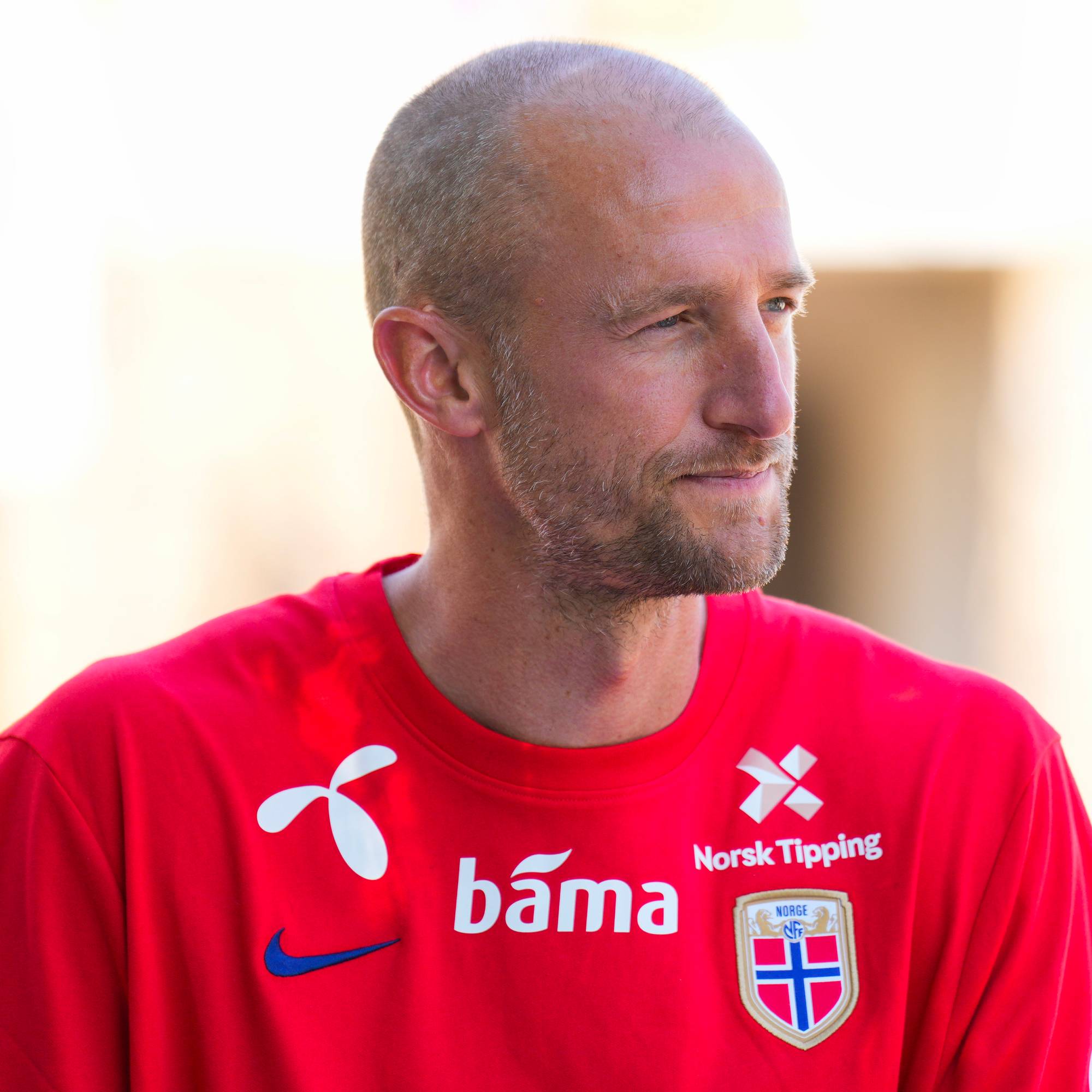 En mann uten hår med rød drakt. 