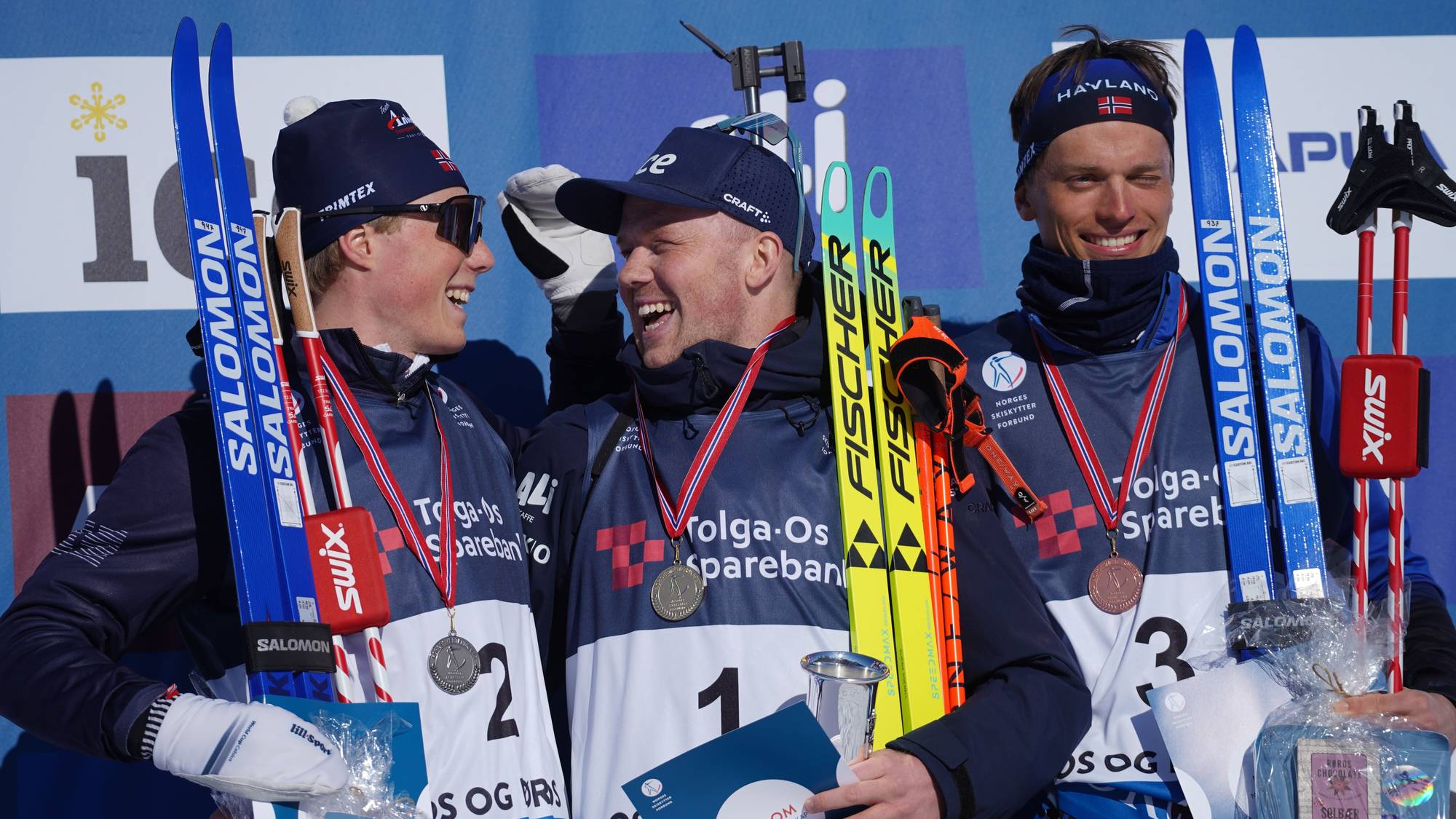Tre skiskyttere som smiler på seierspallen