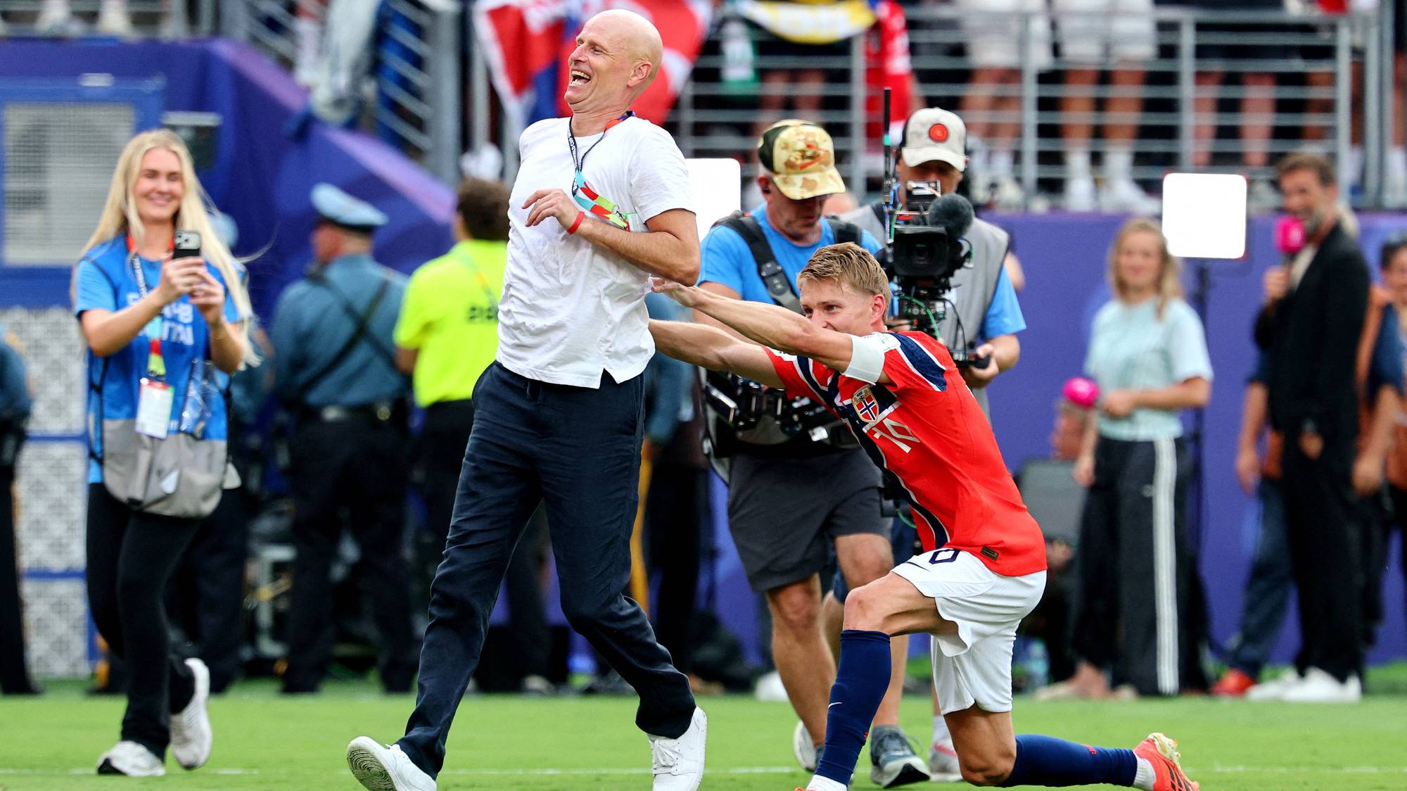 Martin Ødegaard feirer med landslagstrener Ståle Solbakken på en fotballbane. (Bildebeskrivelsen er laget av en KI-tjeneste)