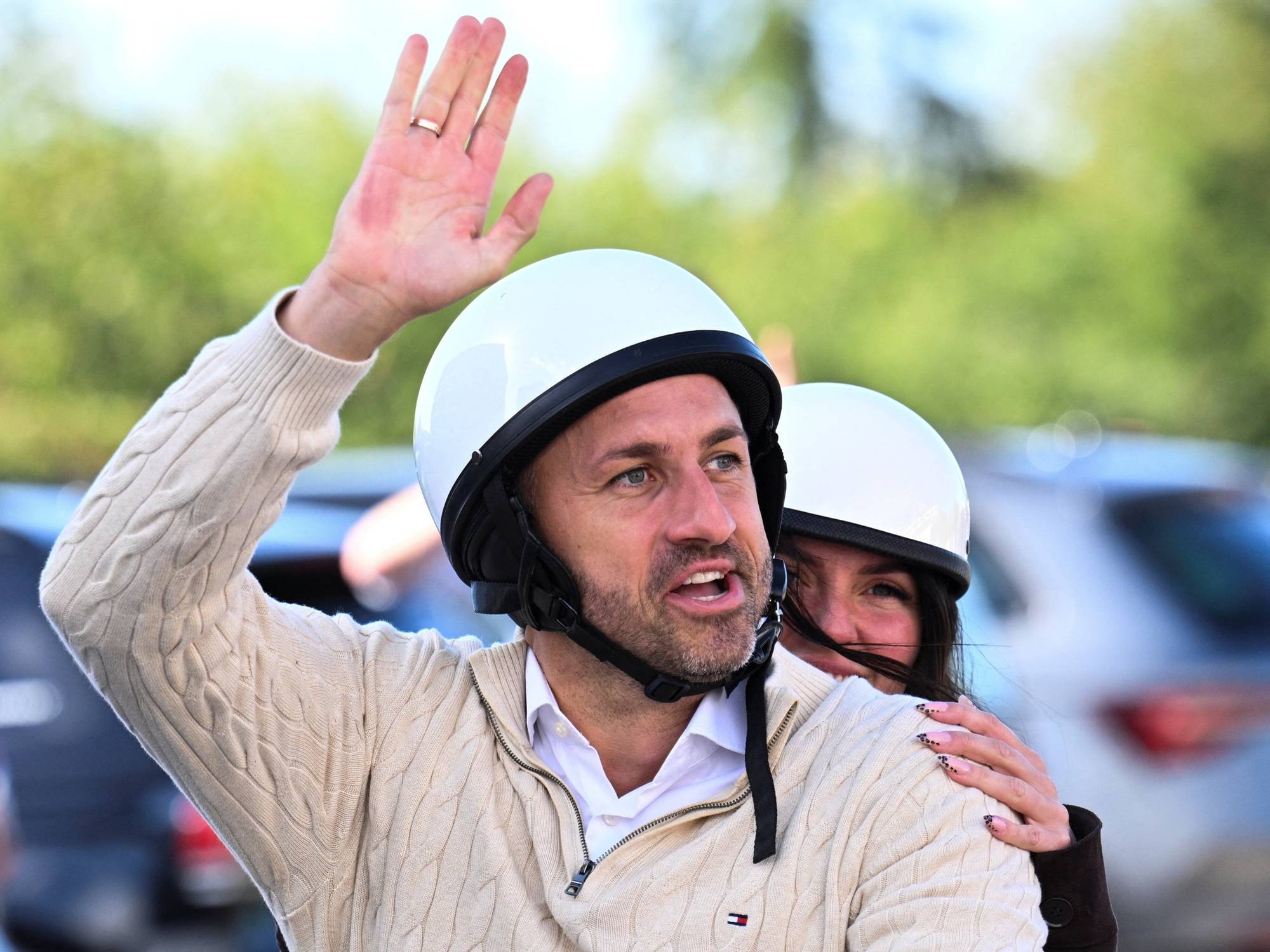 AfD-leder Ulrich Siegmund vinker til publikum fra en scooter. På hodet har han en halvhjelm. Bak han sitter kona Julia, hun også med hjelm. Hun holder seg fast i ektemannens skulder.