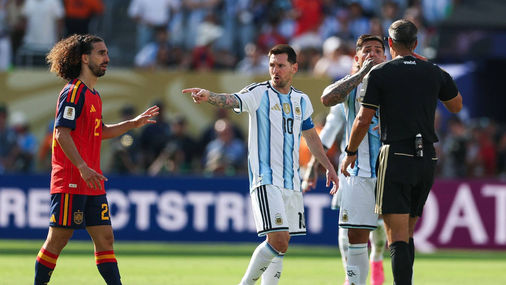 Lionel Messi og andre fotballspillere diskuterer med dommeren under en kamp på en gressbane. (Bildebeskrivelsen er laget av en KI-tjeneste)