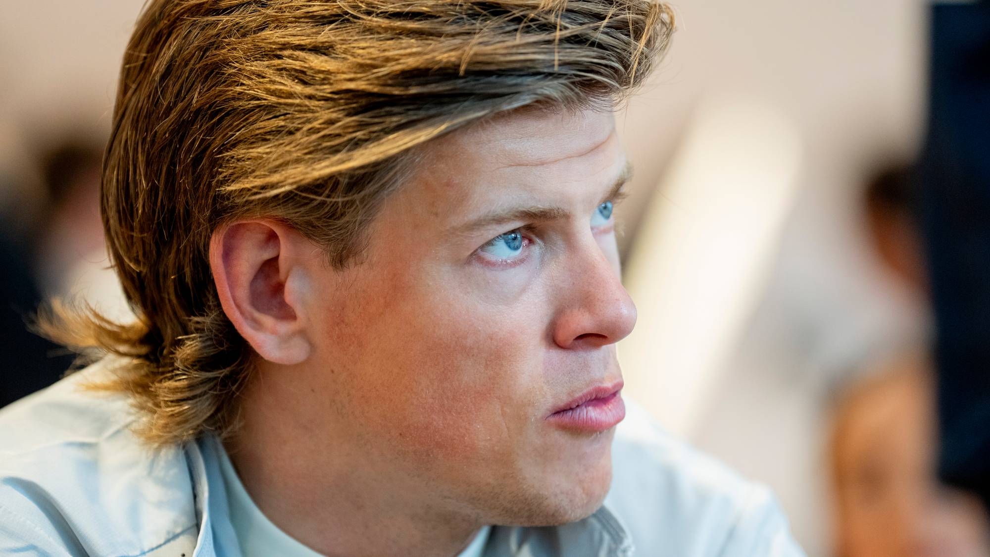 Et nærbilde av en mann med blondt hår og blå øyne. Han er iført en lys skjorte. En NTB-logo er plassert over ansiktet hans. (Bildebeskrivelsen er laget av en KI-tjeneste)