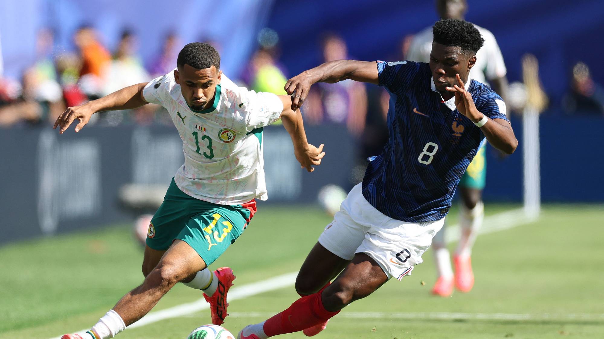 Fotballspillere fra Senegal og Frankrike kjemper om ballen under en kamp på gressbane. (Bildebeskrivelsen er laget av en KI-tjeneste)
