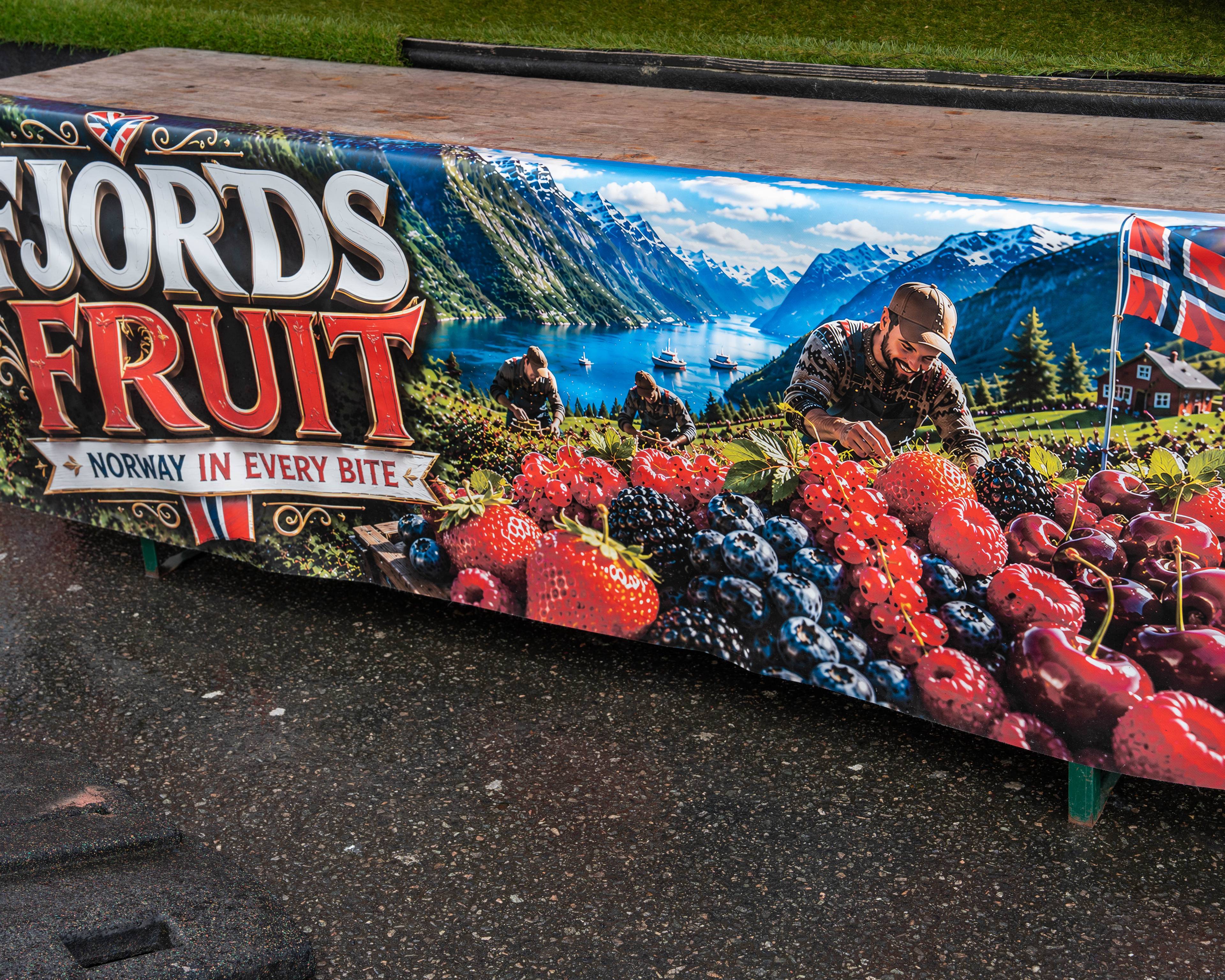 Reklamebanner for Fjords Fruit med bilde av personer som plukker bær i et norsk fjordlandskap. (Bildebeskrivelsen er laget av en KI-tjeneste)