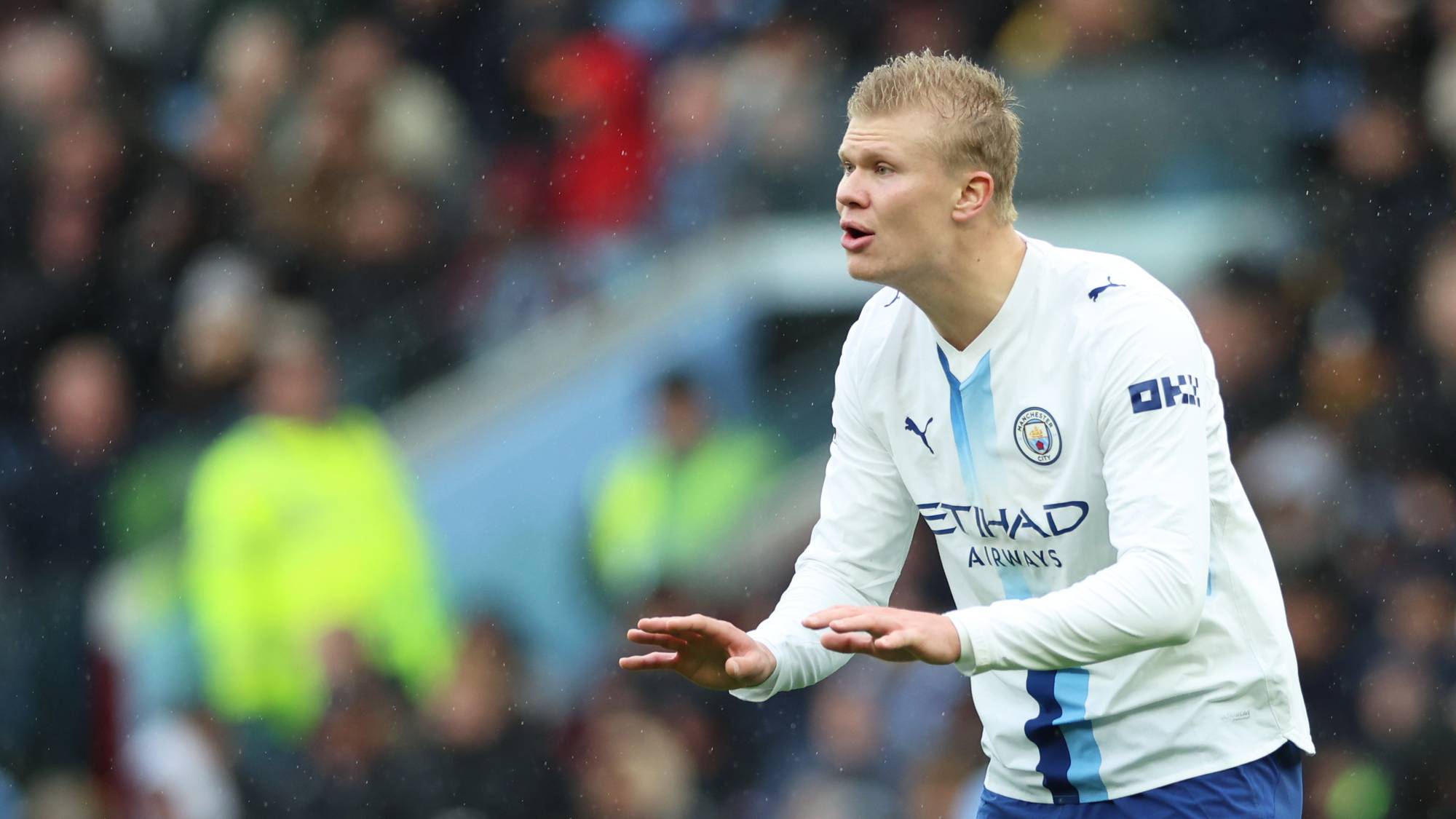 Erling Braut Haaland i Manchester City-drakt på fotballbane med publikum i bakgrunnen. (Bildebeskrivelsen er laget av en KI-tjeneste)