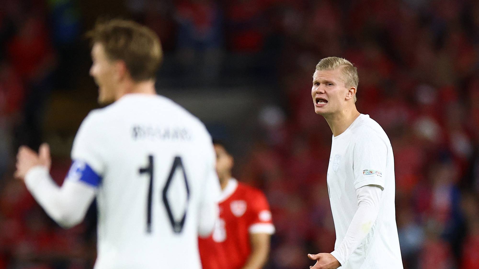 Erling Braut Haaland ser uttrykksfull ut på fotballbanen med Martin Ødegaard i forgrunnen. (Bildebeskrivelsen er laget av en KI-tjeneste)