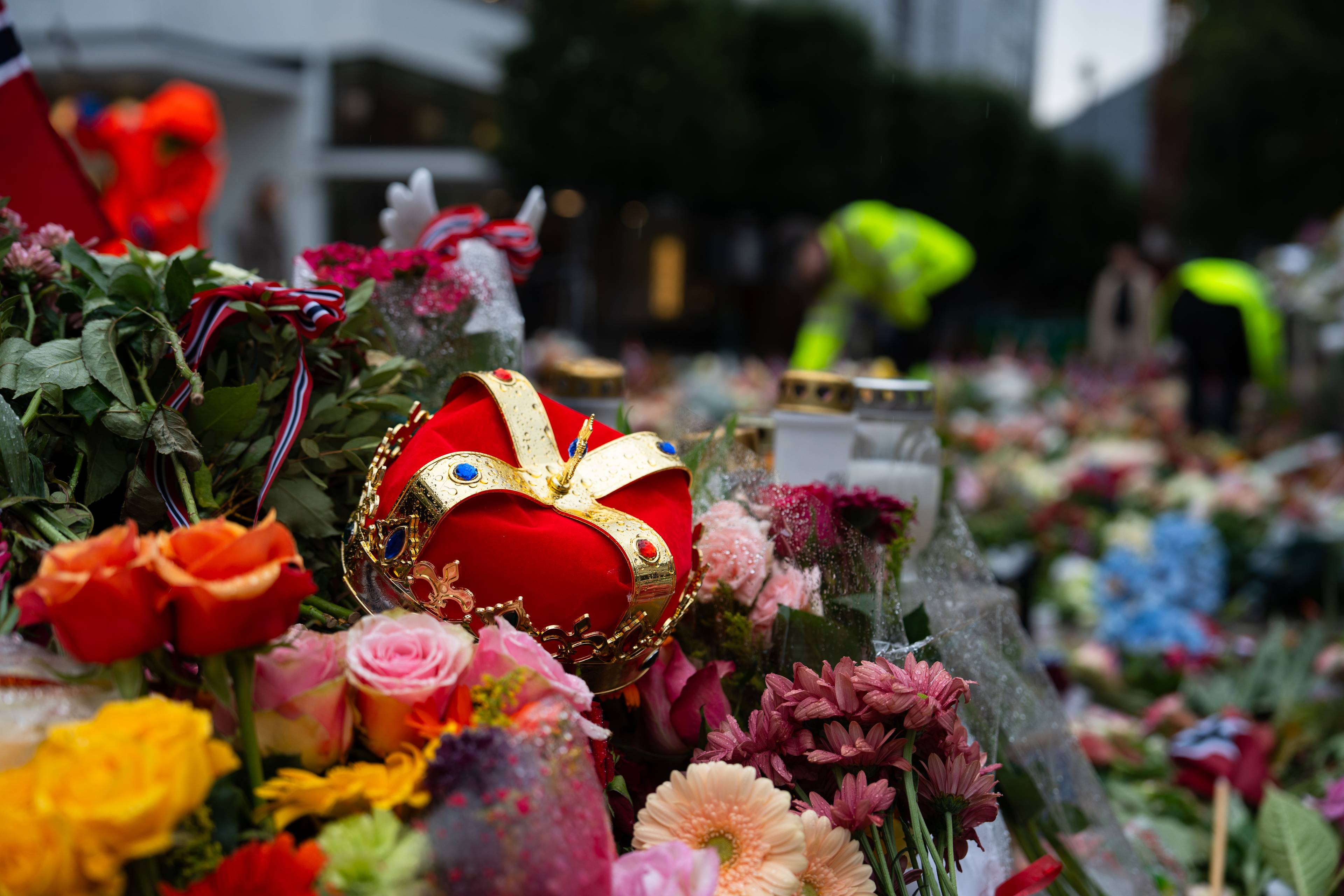 Tusenvis av blomster er lagt ned på og rundt Den blå steinen i Bergen. Det er også ein krone som er dukka opp i blomsterhavet.