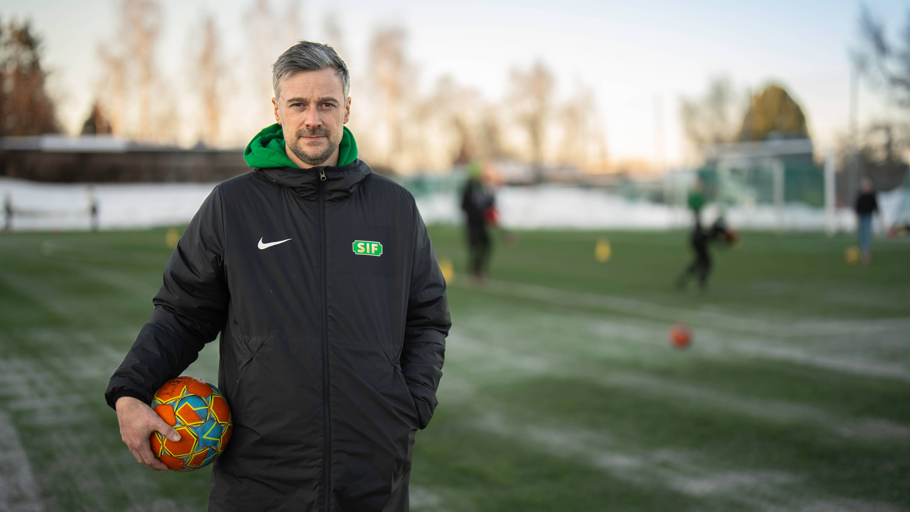 Mann står på en fotballbane med en ball