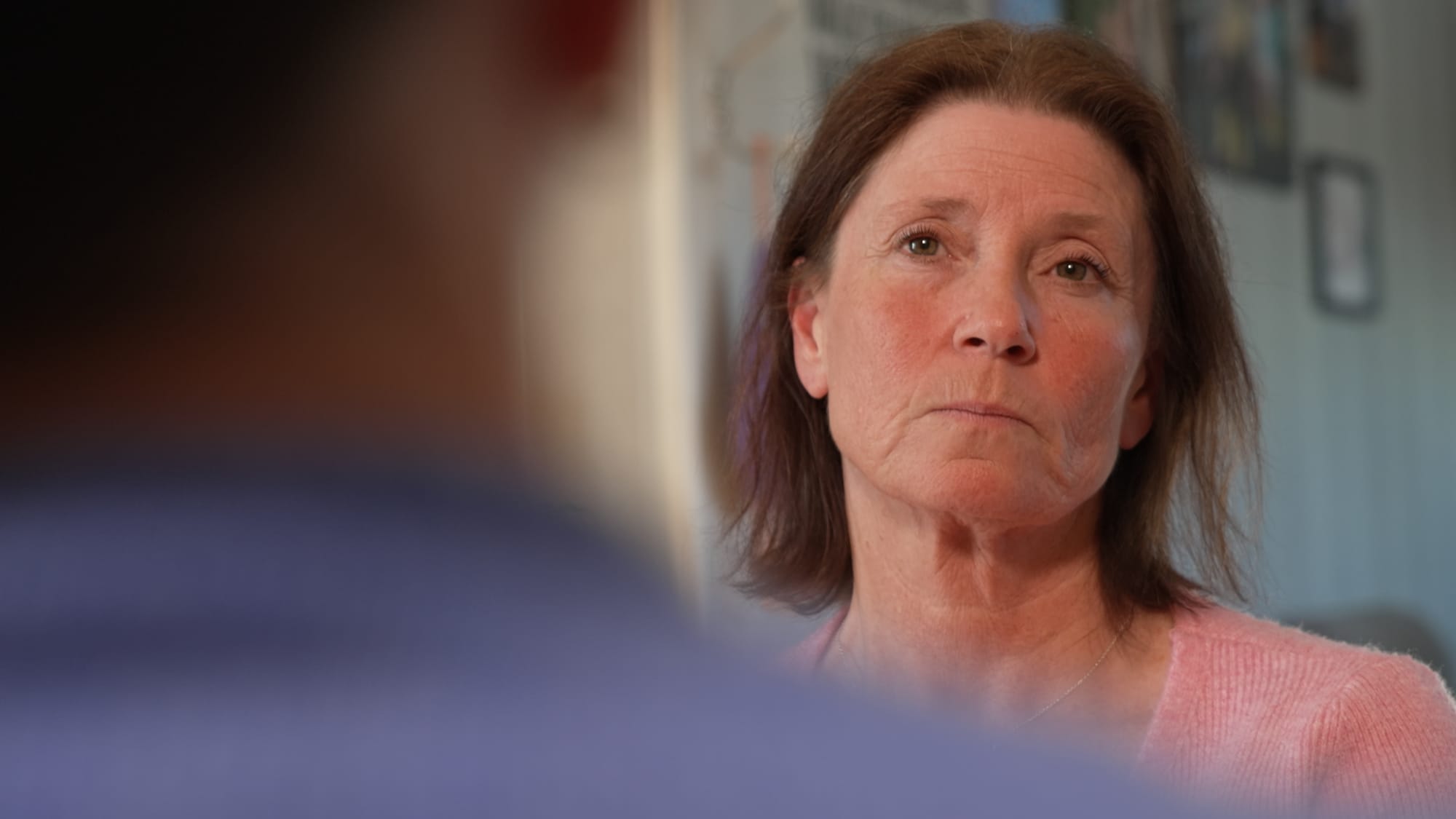 Viser kvinne i rosa, ser på intervjuer (avskåret) med blå jakke