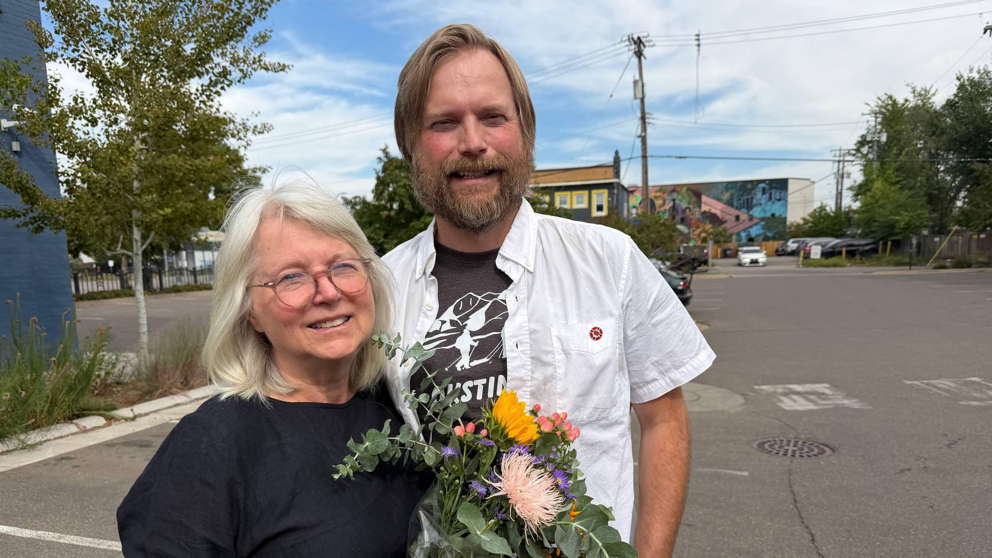 En kvinne og en mann står sammen utendørs, kvinnen holder en blomsterbukett. (Bildebeskrivelsen er laget av en KI-tjeneste)
