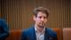 Stian Lysberg Solum / NTB En mann i dress sitter foran en vegg av trepaneler. Han har brunt, krøllete hår og ser til siden. I bakgrunnen er det to personer til som sitter. (Bildebeskrivelsen er laget av en KI-tjeneste)