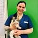 Privat Elena Olsen står foran en grønn vegg i en blå veterinærskjorte. Hun holder en katt.