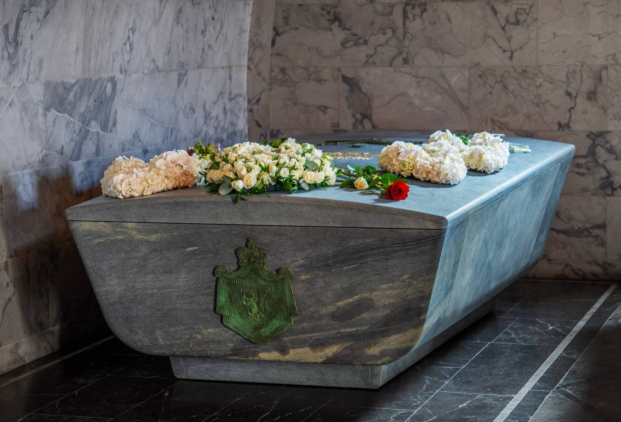 Kongelig sarkofag i stein med hvite blomster og en rød rose i det kongelige mausoleet.