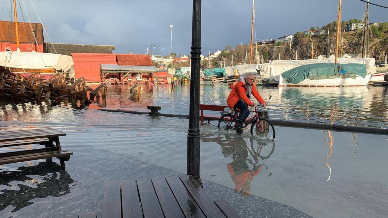 En mann sykler med vann langt oppover sykkelhjulene i Ålesund sentrum.