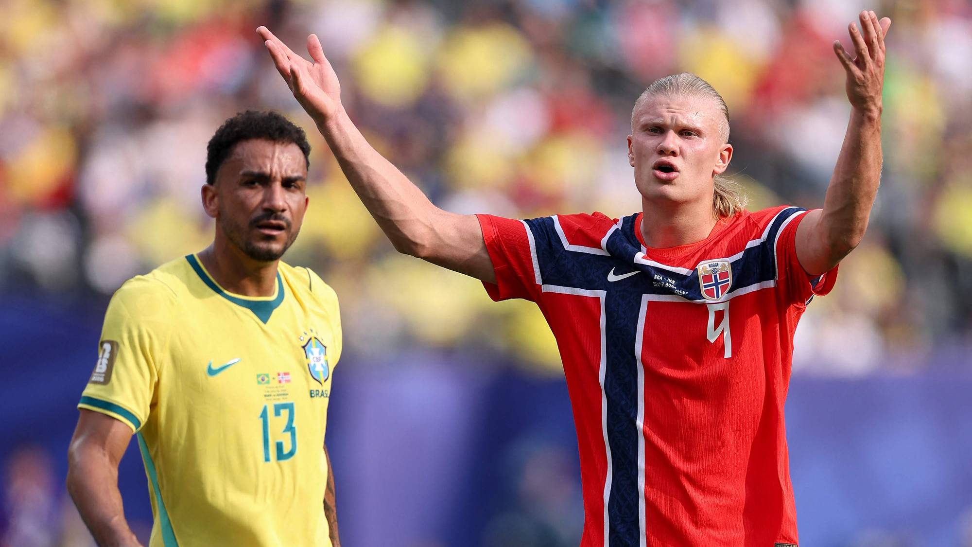 Erling Braut Haaland i norsk landslagsdrakt gestikulerer foran en brasiliansk fotballspiller. (Bildebeskrivelsen er laget av en KI-tjeneste)