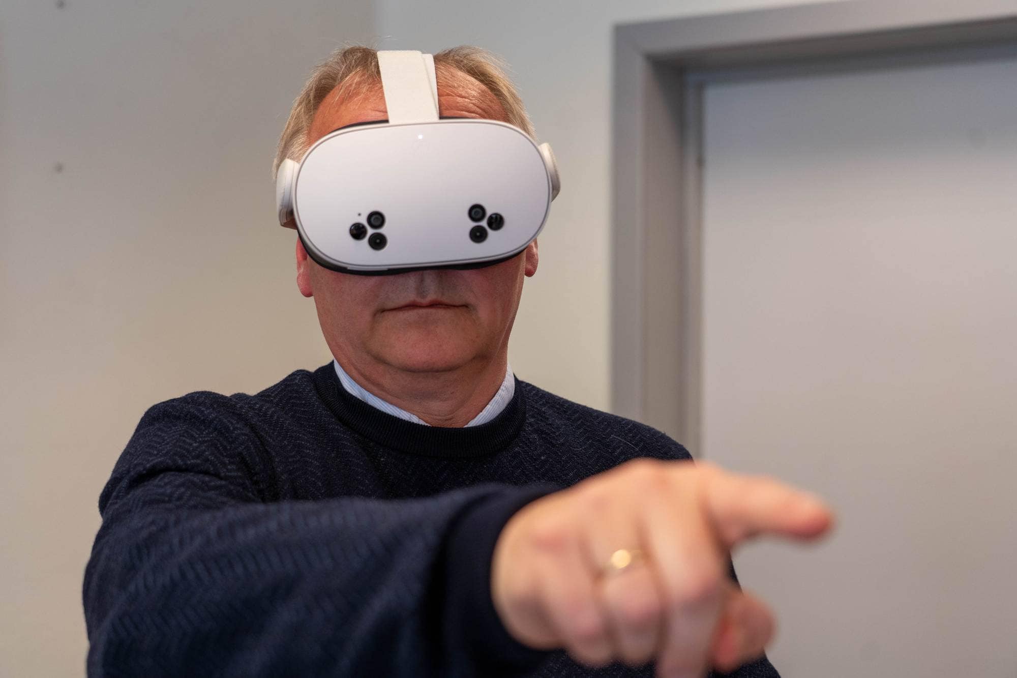 Forsker Jan Ivar Røssberg peker med høyre hånd mens han har vr-headset på.