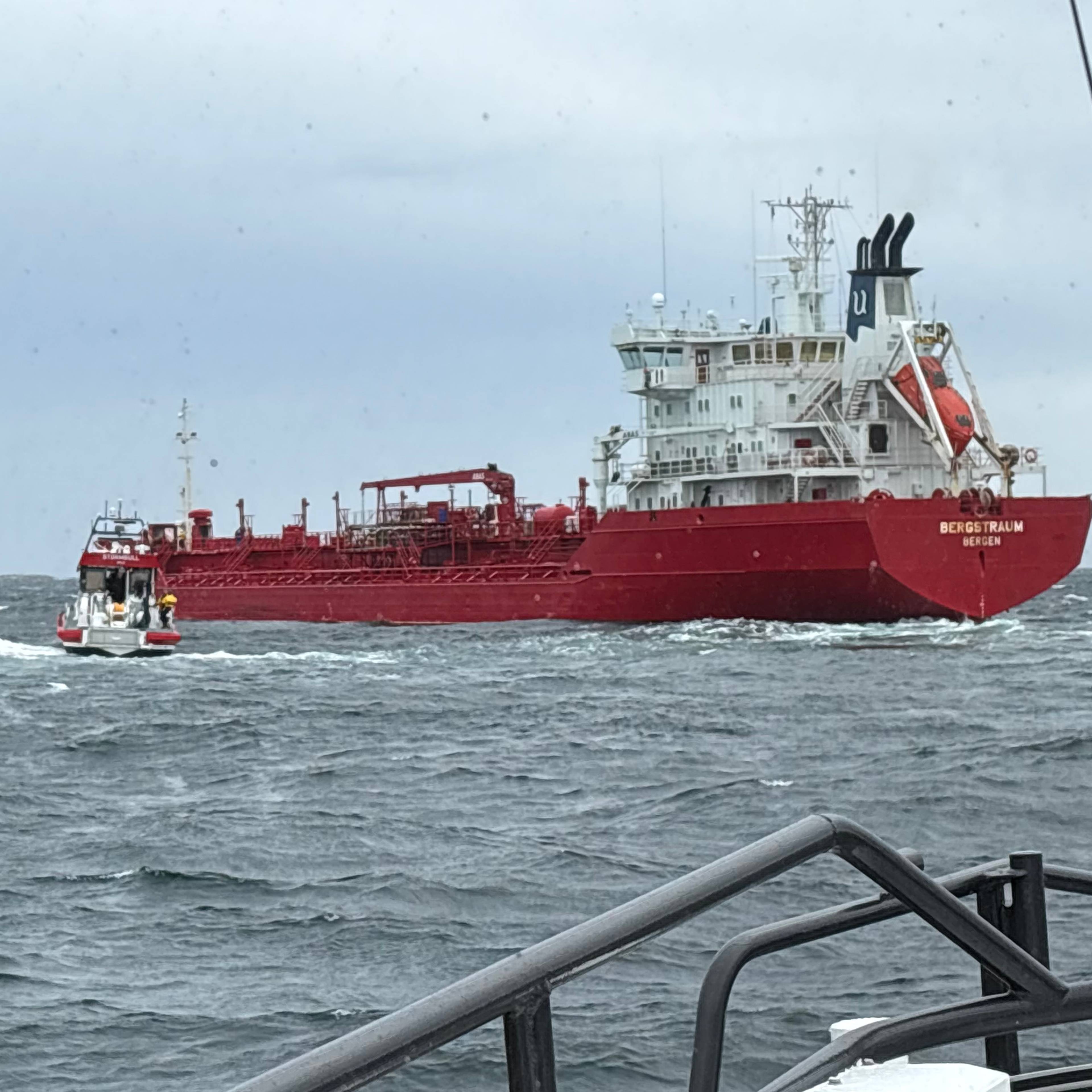 Det røde skipet Bergstraum navigerer i åpent hav, fulgt av en mindre rød redningsskøyte. (Bildebeskrivelsen er laget av en KI-tjeneste)