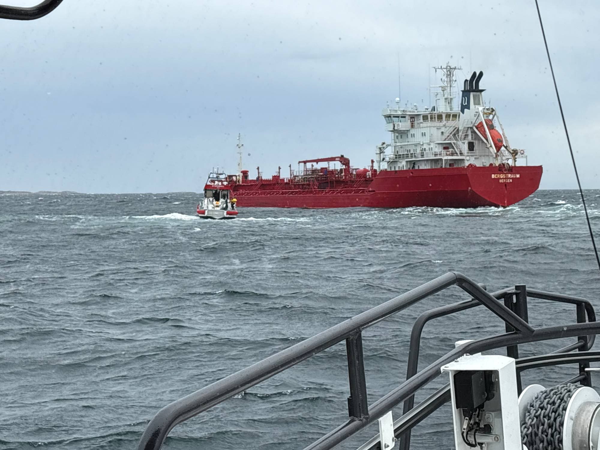 Det røde skipet Bergstraum navigerer i åpent hav, fulgt av en mindre rød redningsskøyte. (Bildebeskrivelsen er laget av en KI-tjeneste)