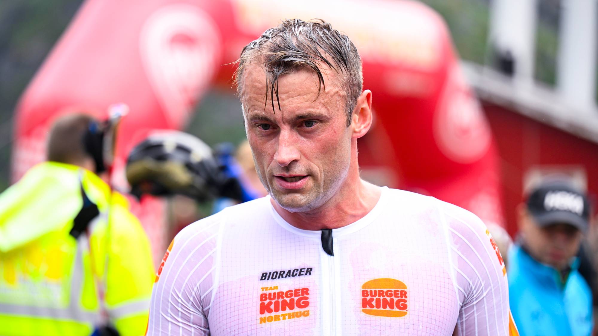 Petter Northug etter et skirenn, med svett ansikt og hvit konkurransedrakt med sponsorlogoer. (Bildebeskrivelsen er laget av en KI-tjeneste)