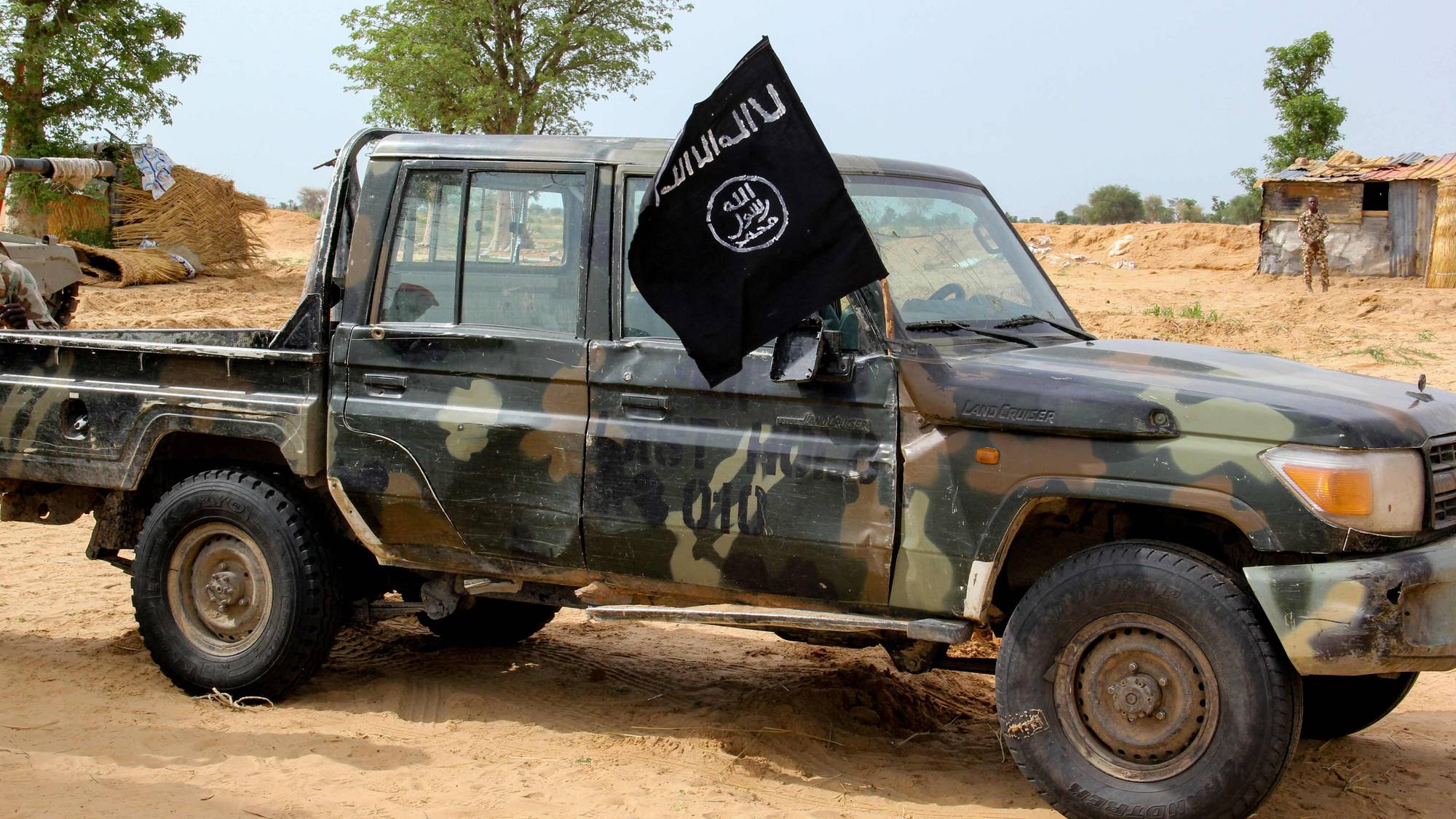 Pickupruck i militærfarger med svart og hvitt IS-flagg.